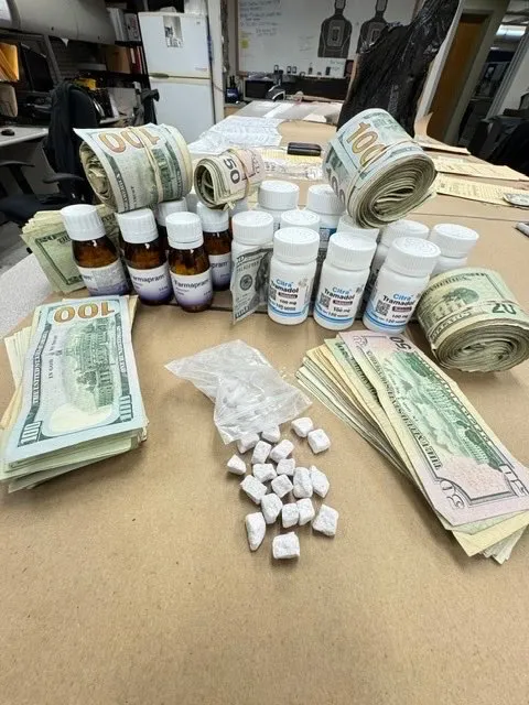 Narcotics, prescription pills, and stacks of cash seized during an operation.