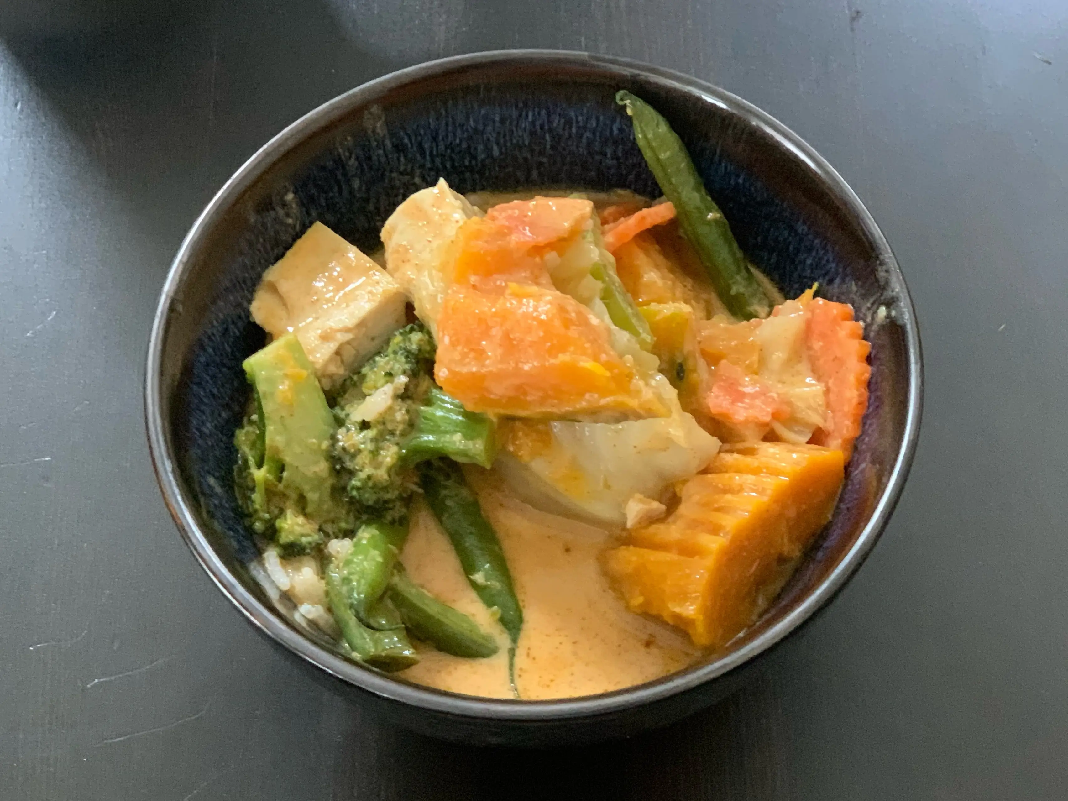 vegetable curry with squash and broccoli in brown bowl
