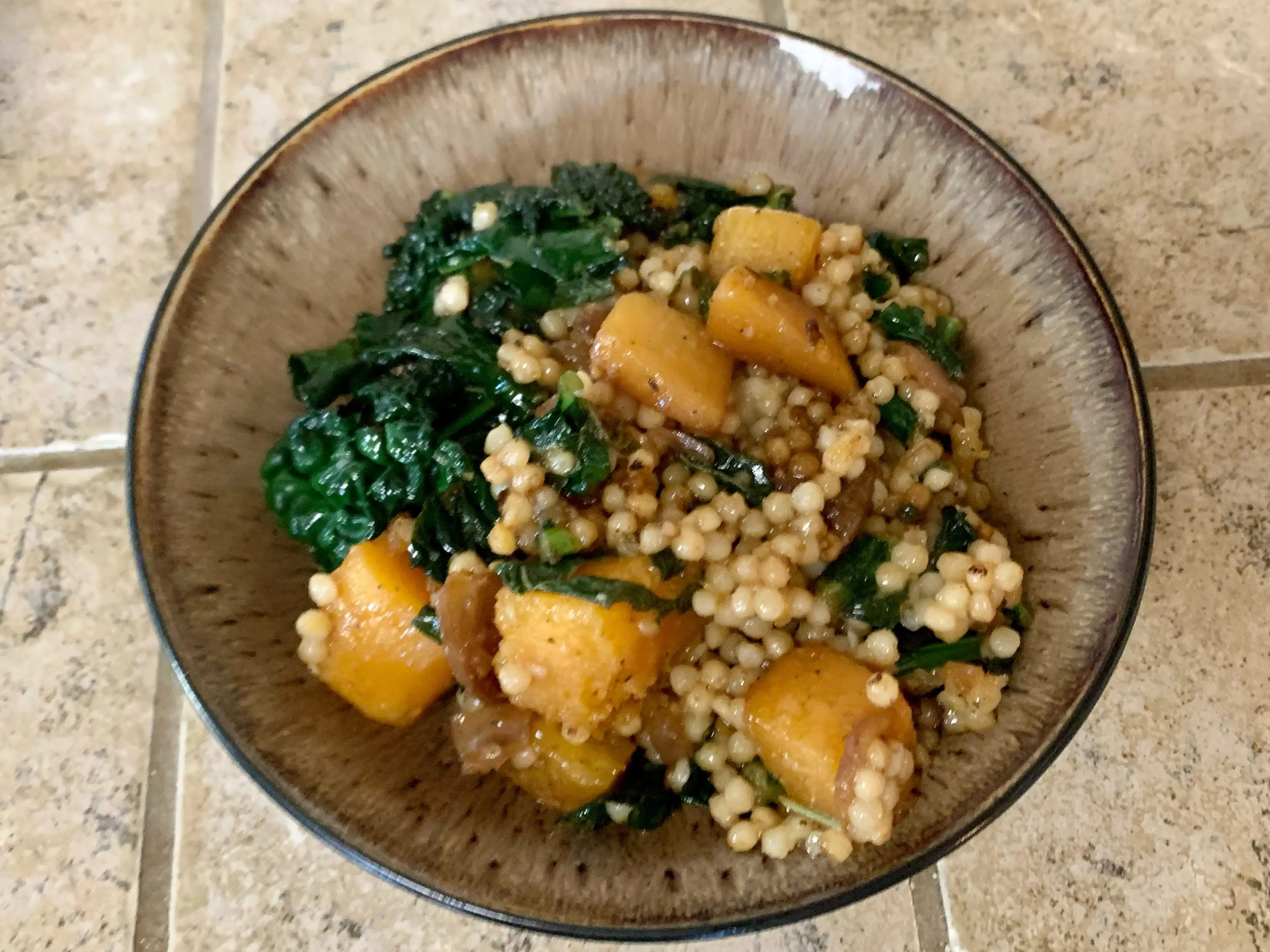 couscous with greens in brown bowl