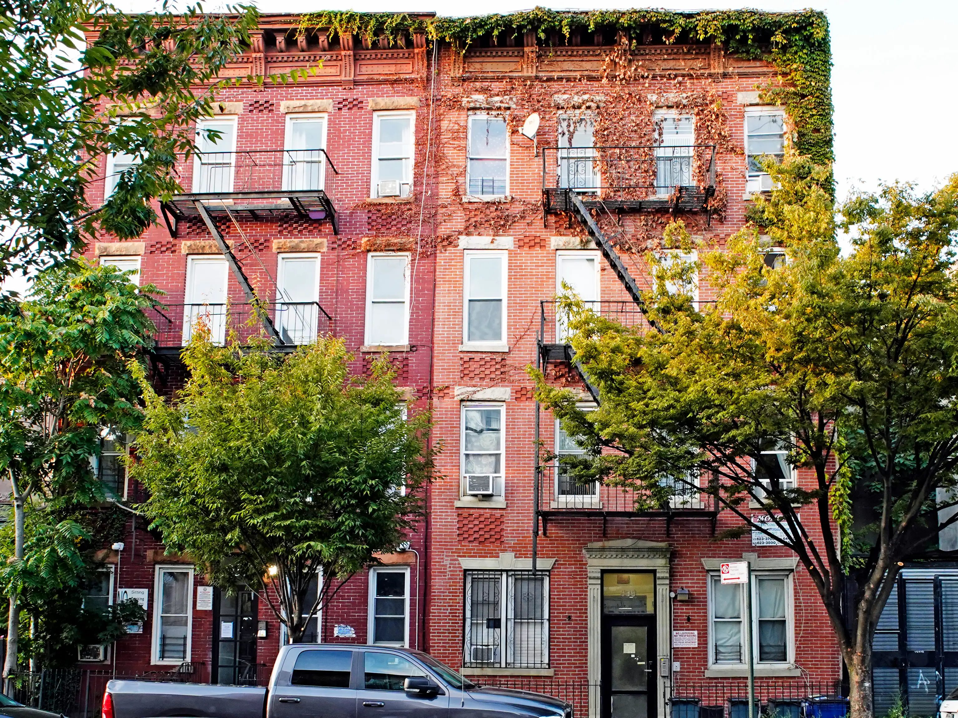 A red brick building in Brooklyn with trees in front of it