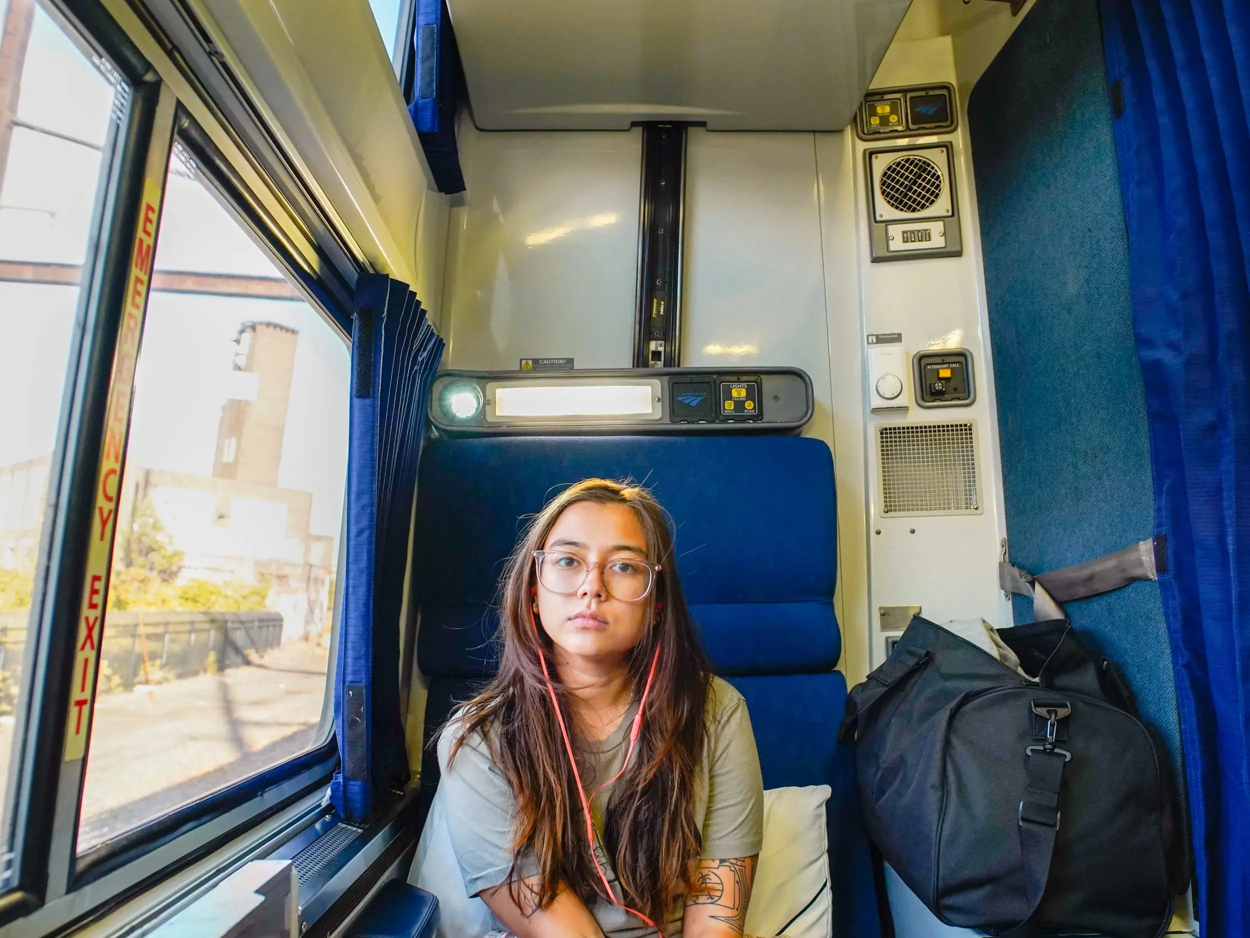 The author sits in a roomette with a window on the left side and a duffel on the right.