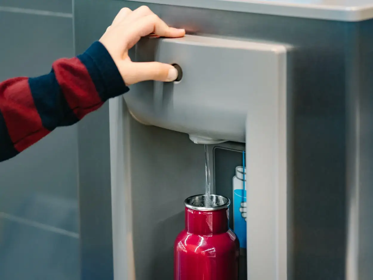 A person fills up their metal water bottle.