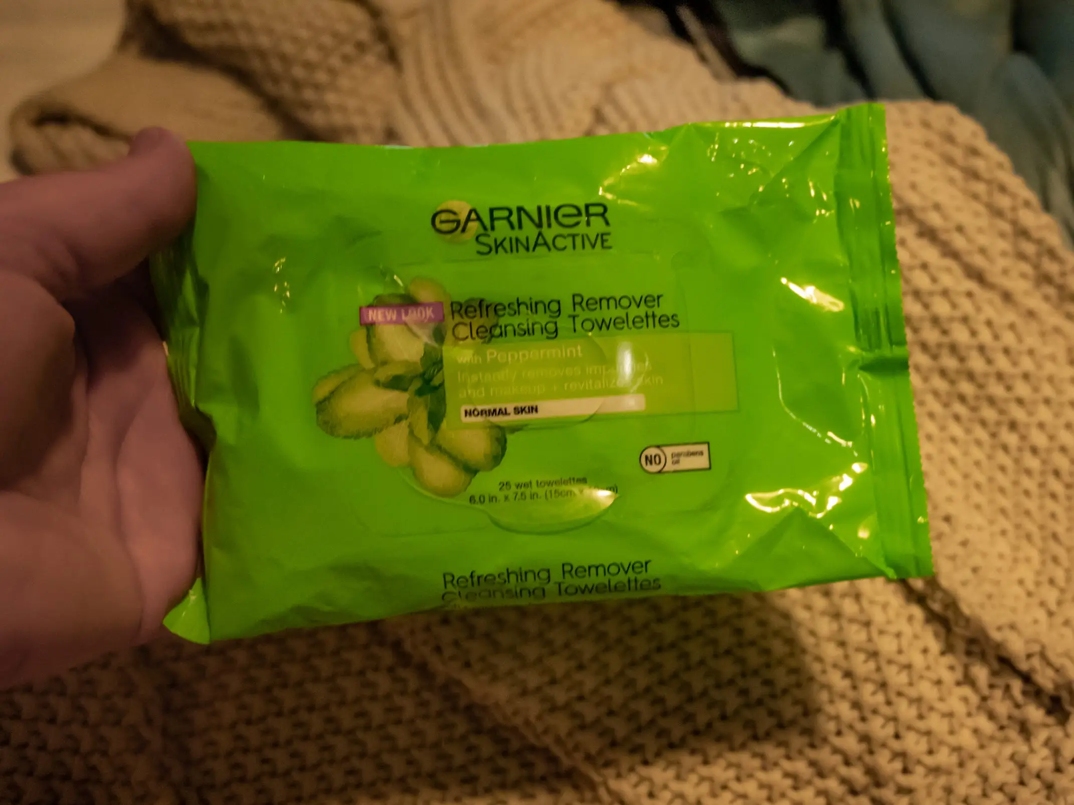 The writer holds a green package of Garnier makeup wipes