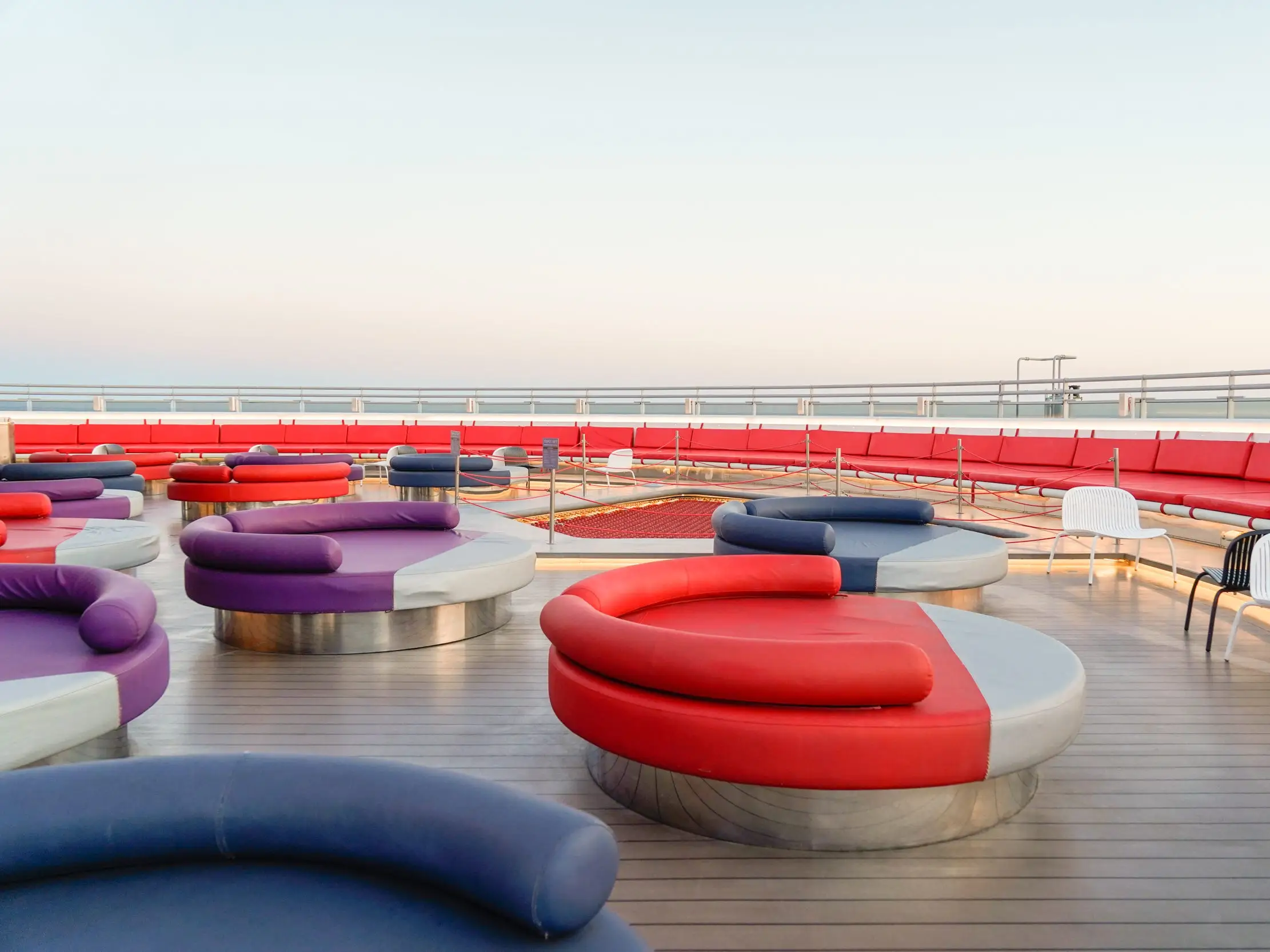 Blue, red, and purple, plush seating on the top deck of a cruise ship with wood floors