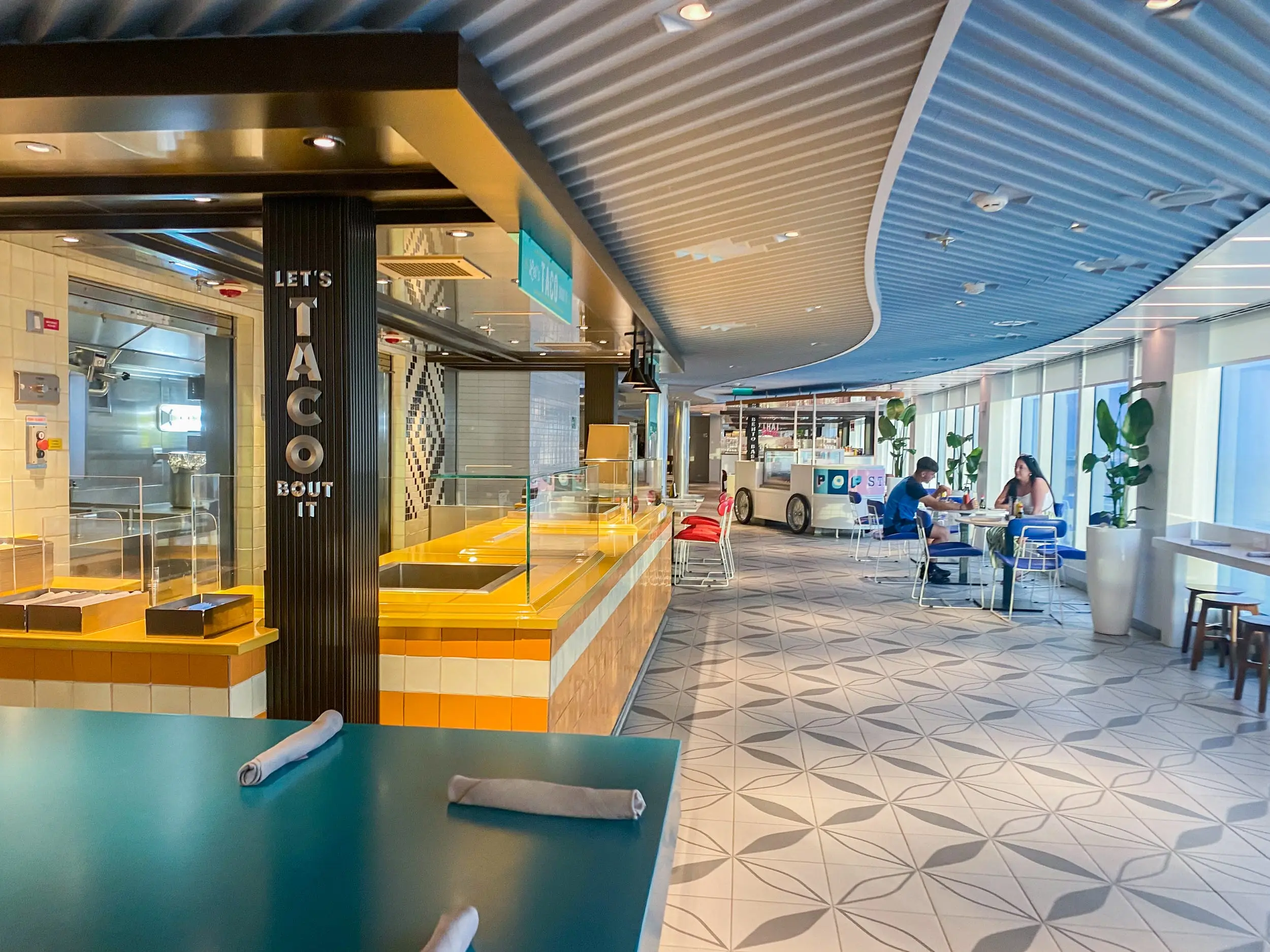 On the left there's a taco counter and on the right here are tables and chairs in a large room with white and gray flooring