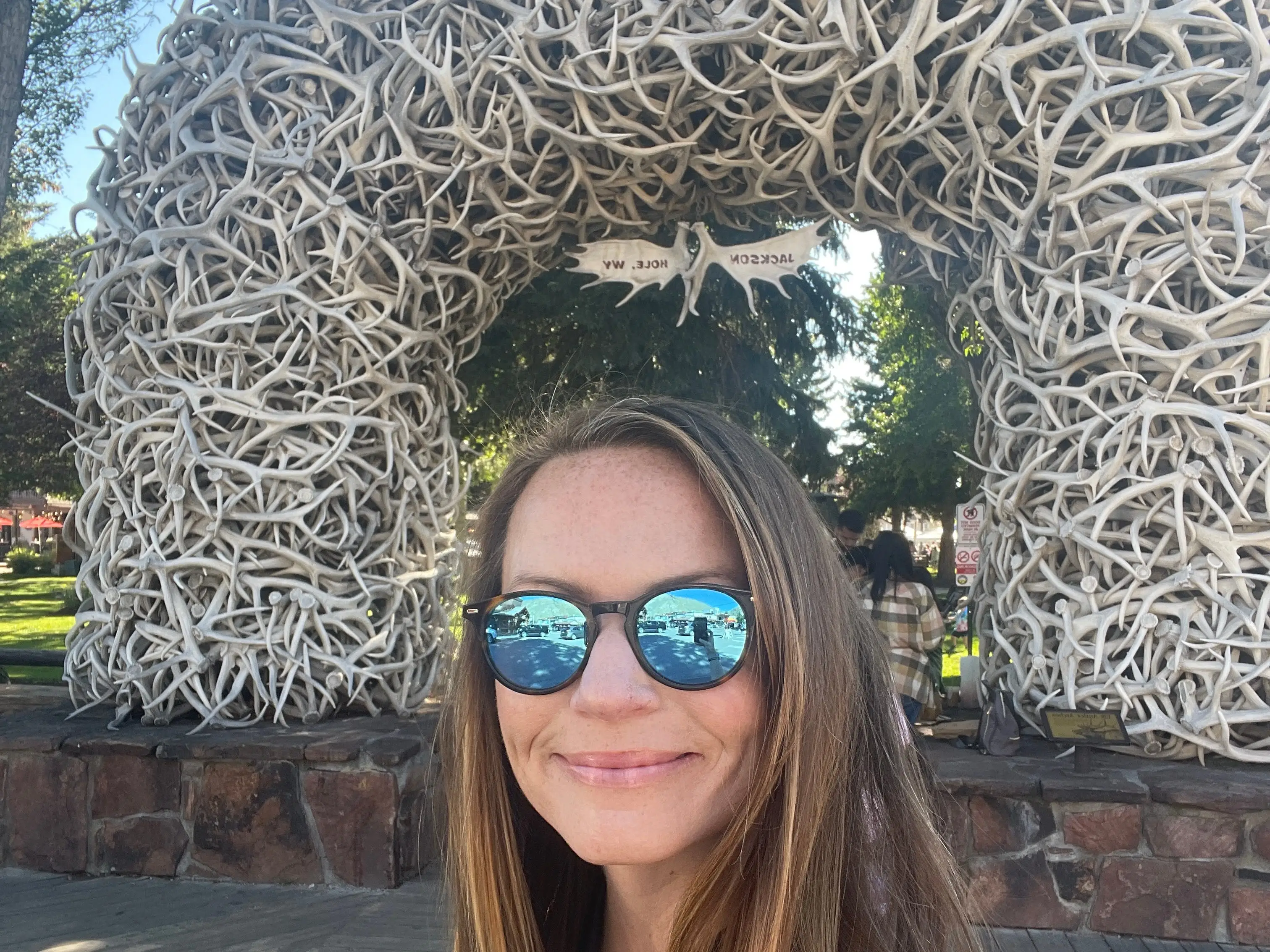 Emily posing in front of an arch made of elk antlers in the Town Square of Wyoming, Jackson.