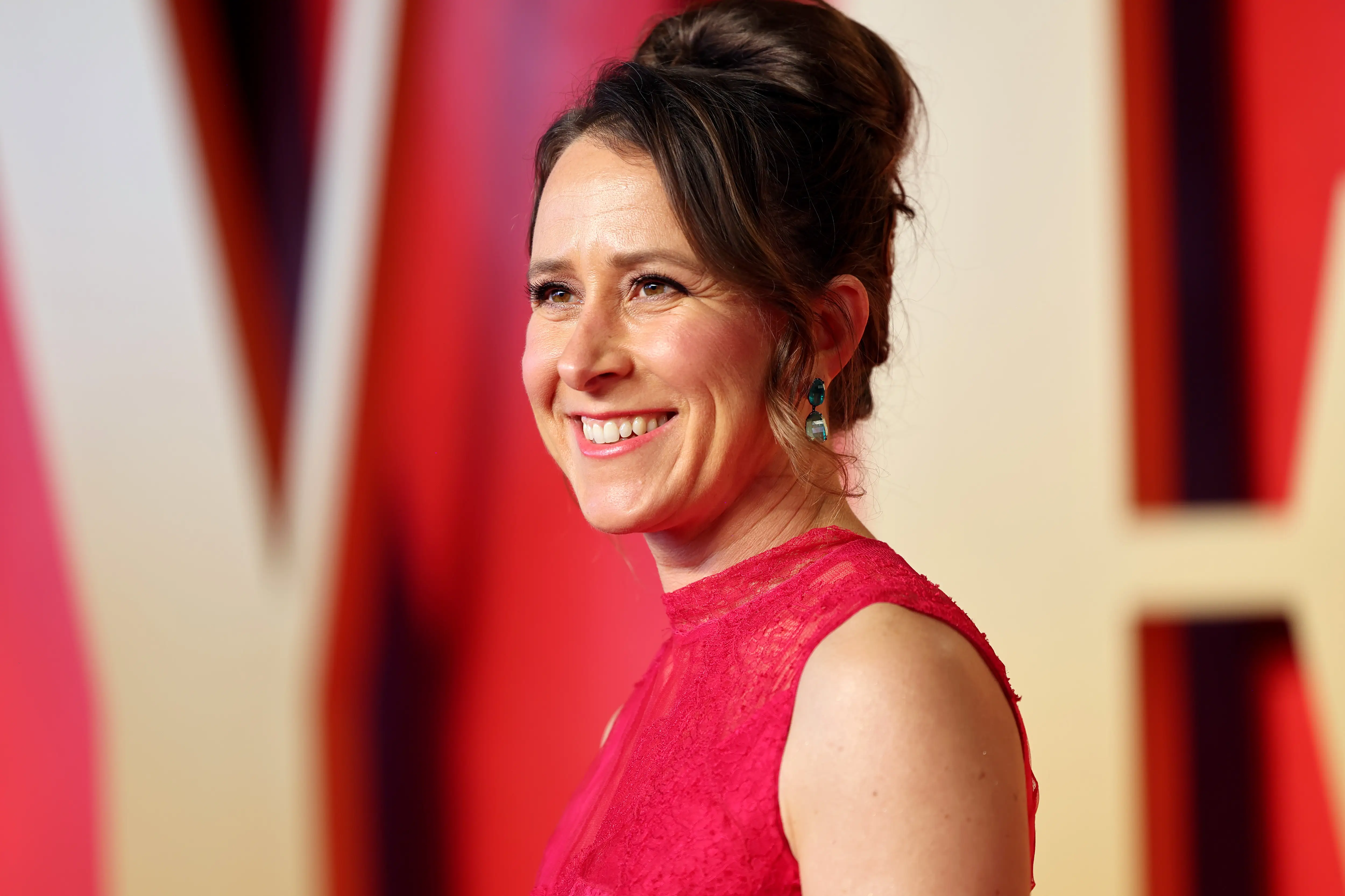 Anne Wojcicki on the red carpet of the Vanity Fair Oscar party, wearing a red dress.