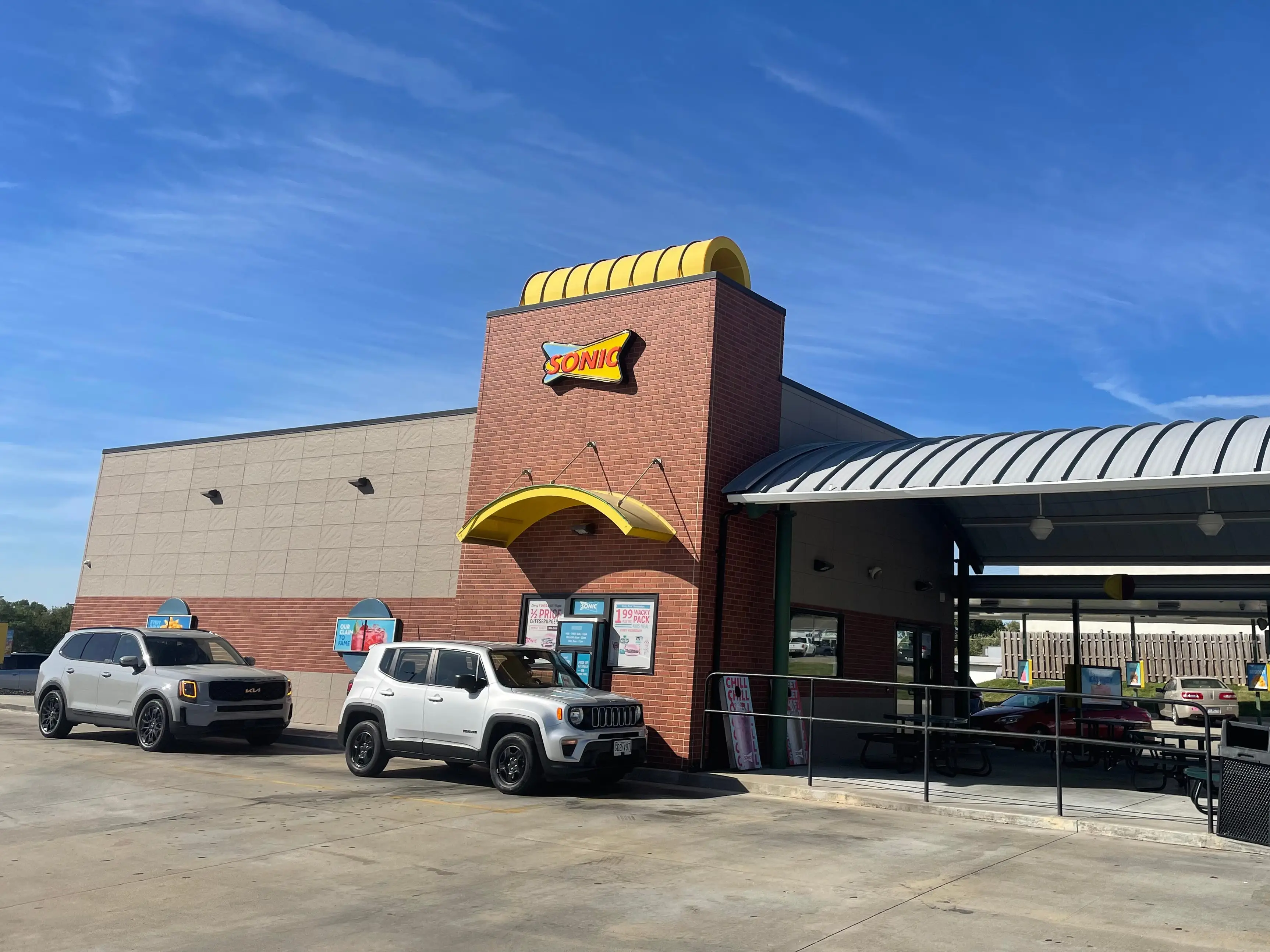 The exterior of a Sonic Drive-In with two cars outside it.