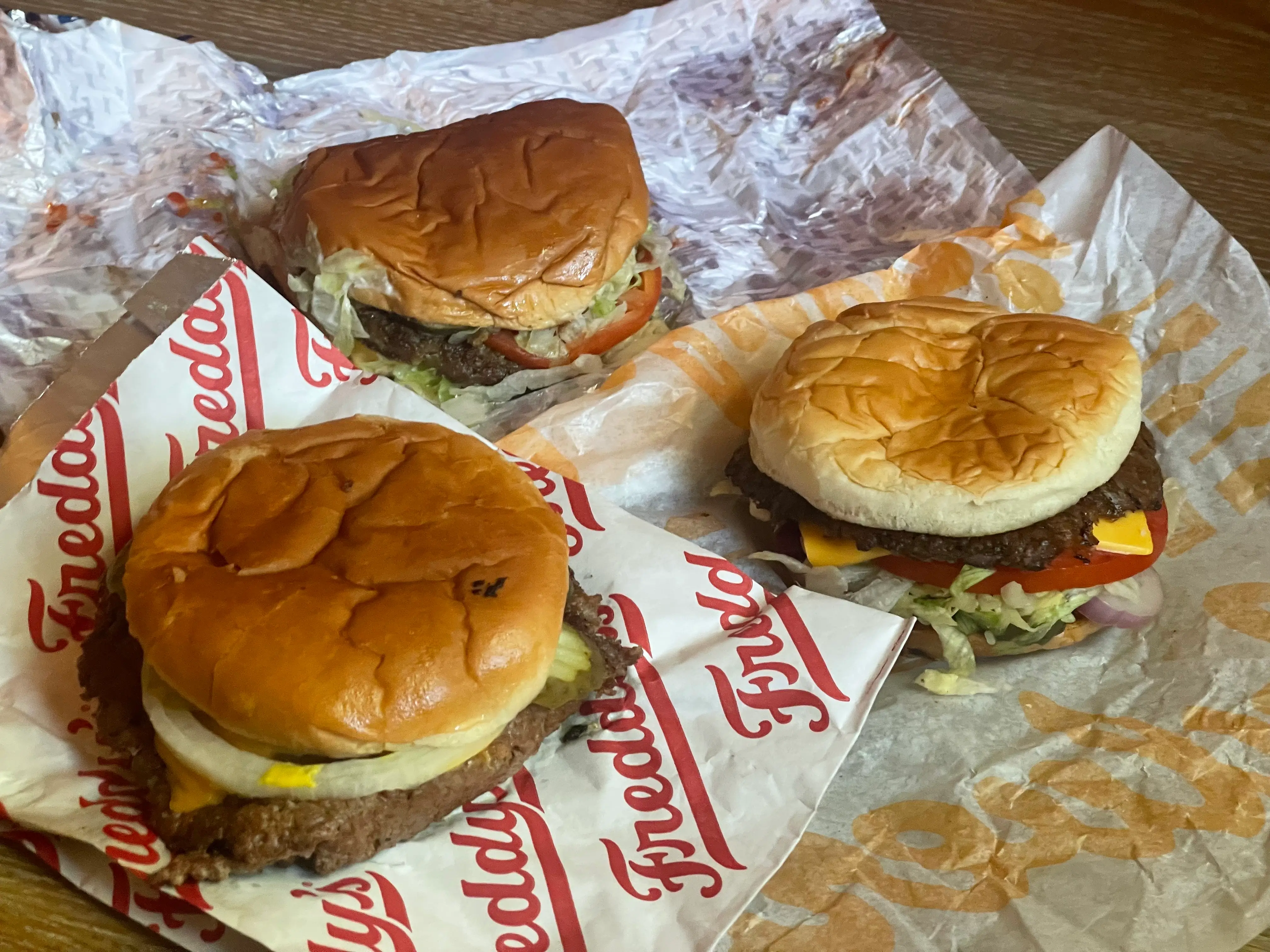 Three cheeseburgers on fast-food wrappings.