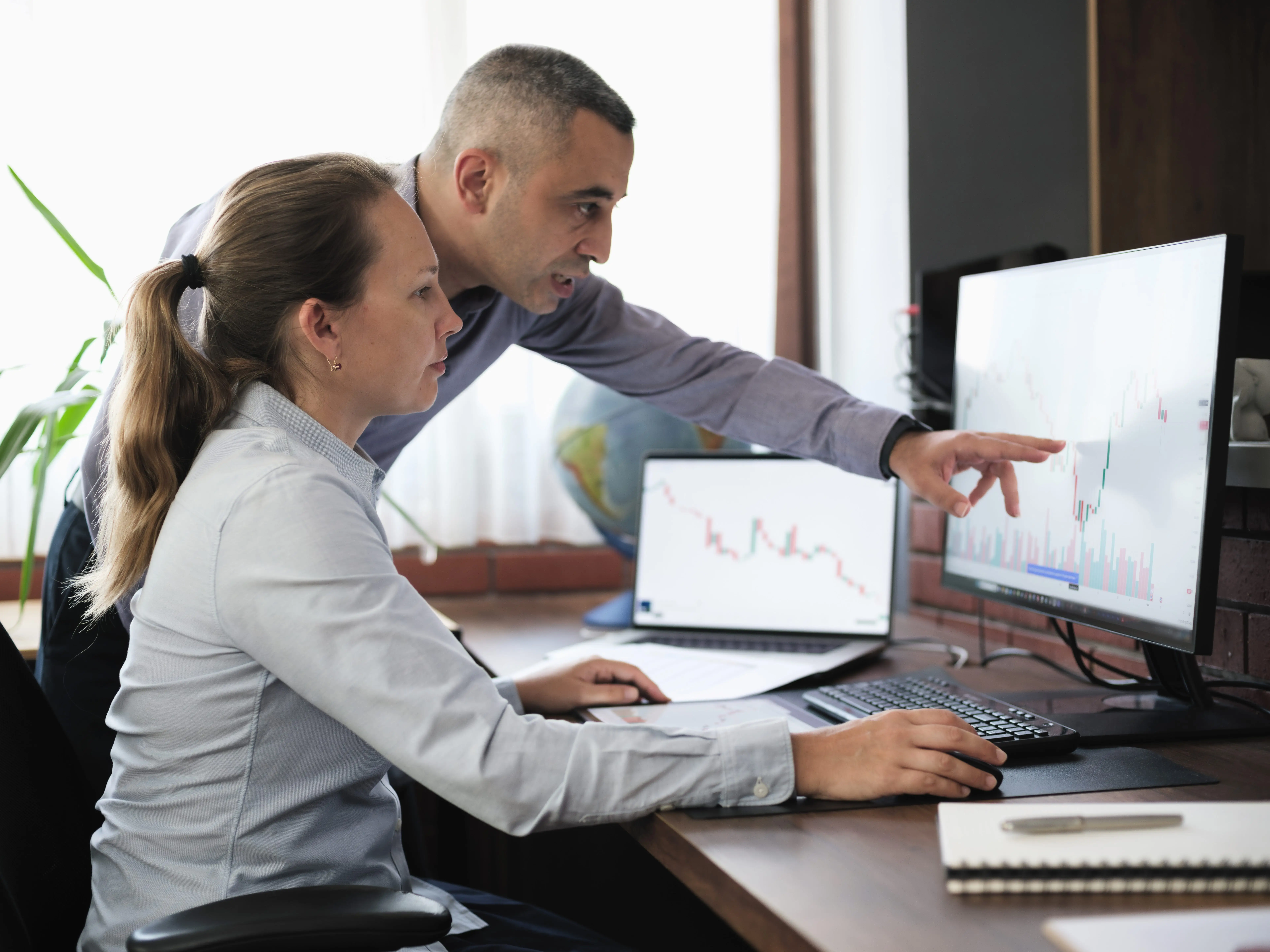 Two people looking at data on a computer screen in an office