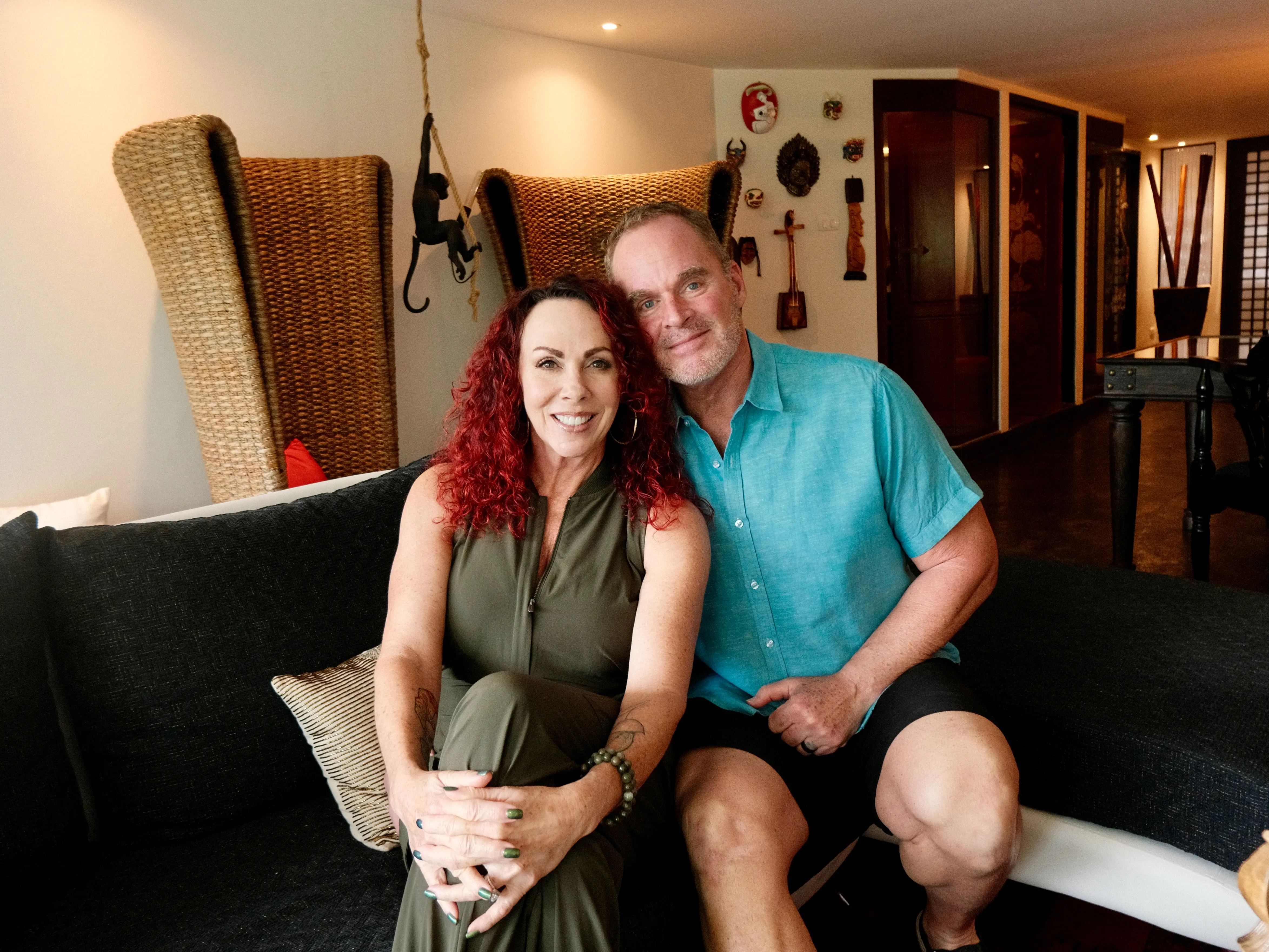 A couple sitting on the couch, posing for a photo.