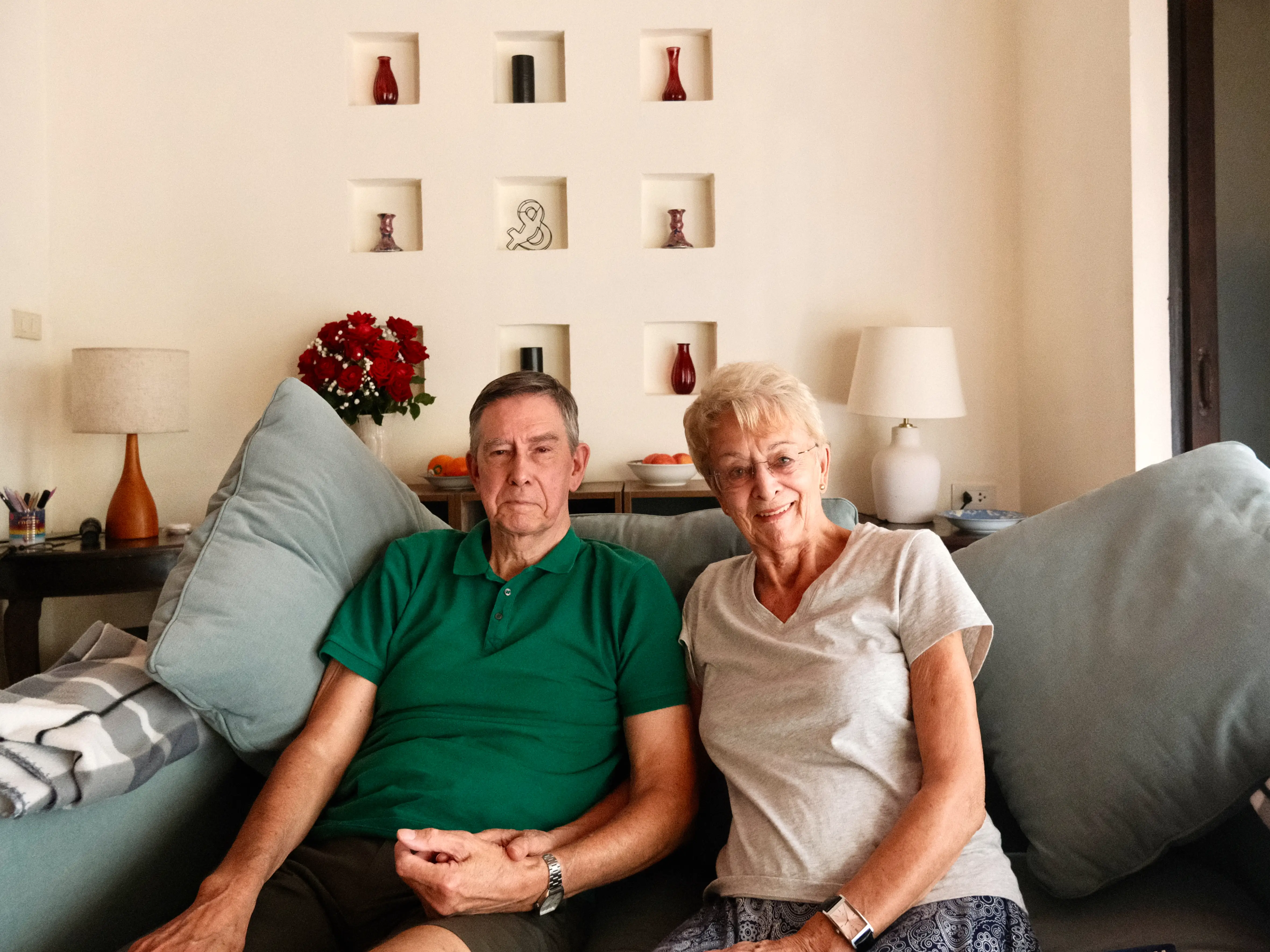 A couple holding hands while sitting on their couch.