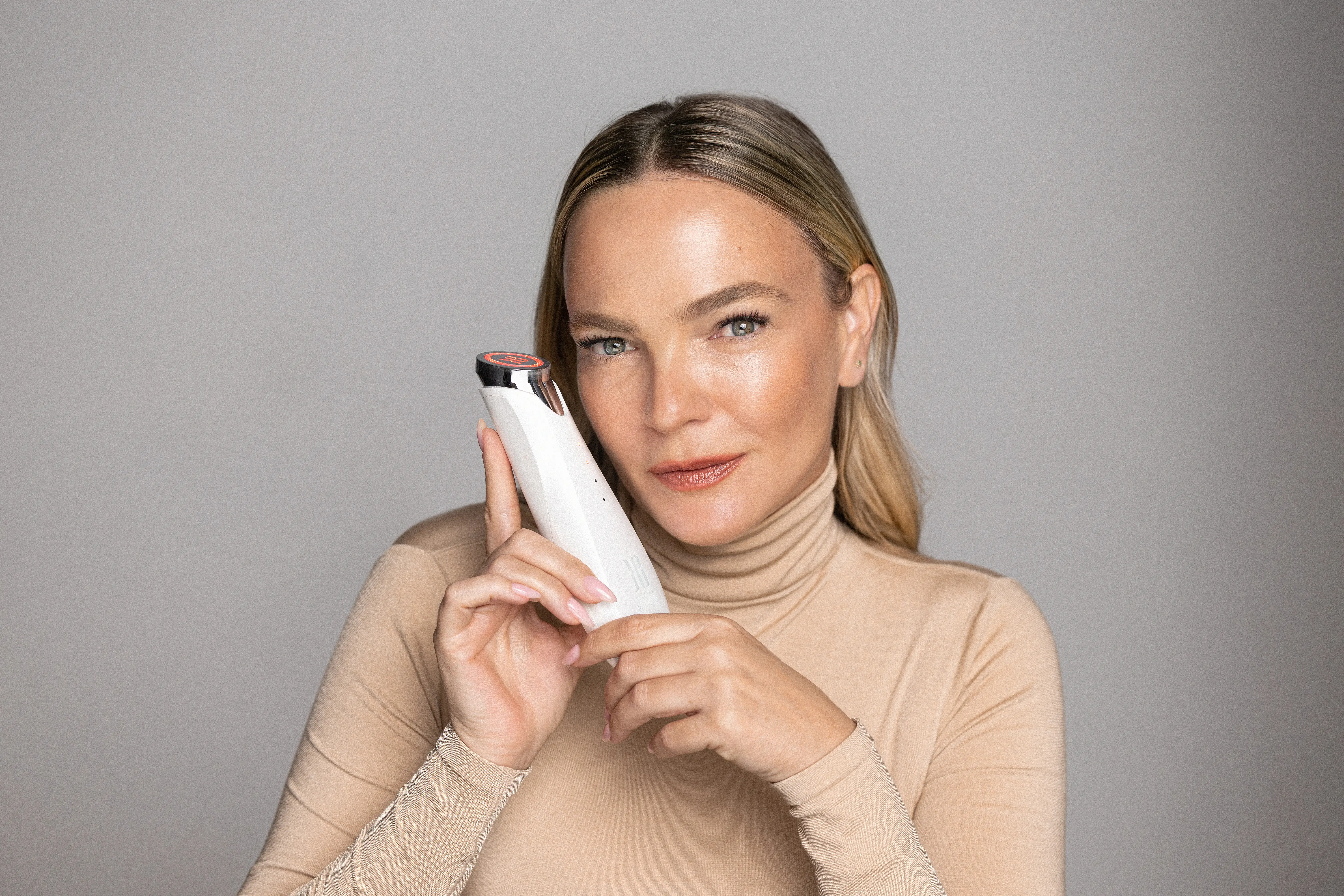 Keren Bartov poses for the camera while holding her red light therapy device, 
