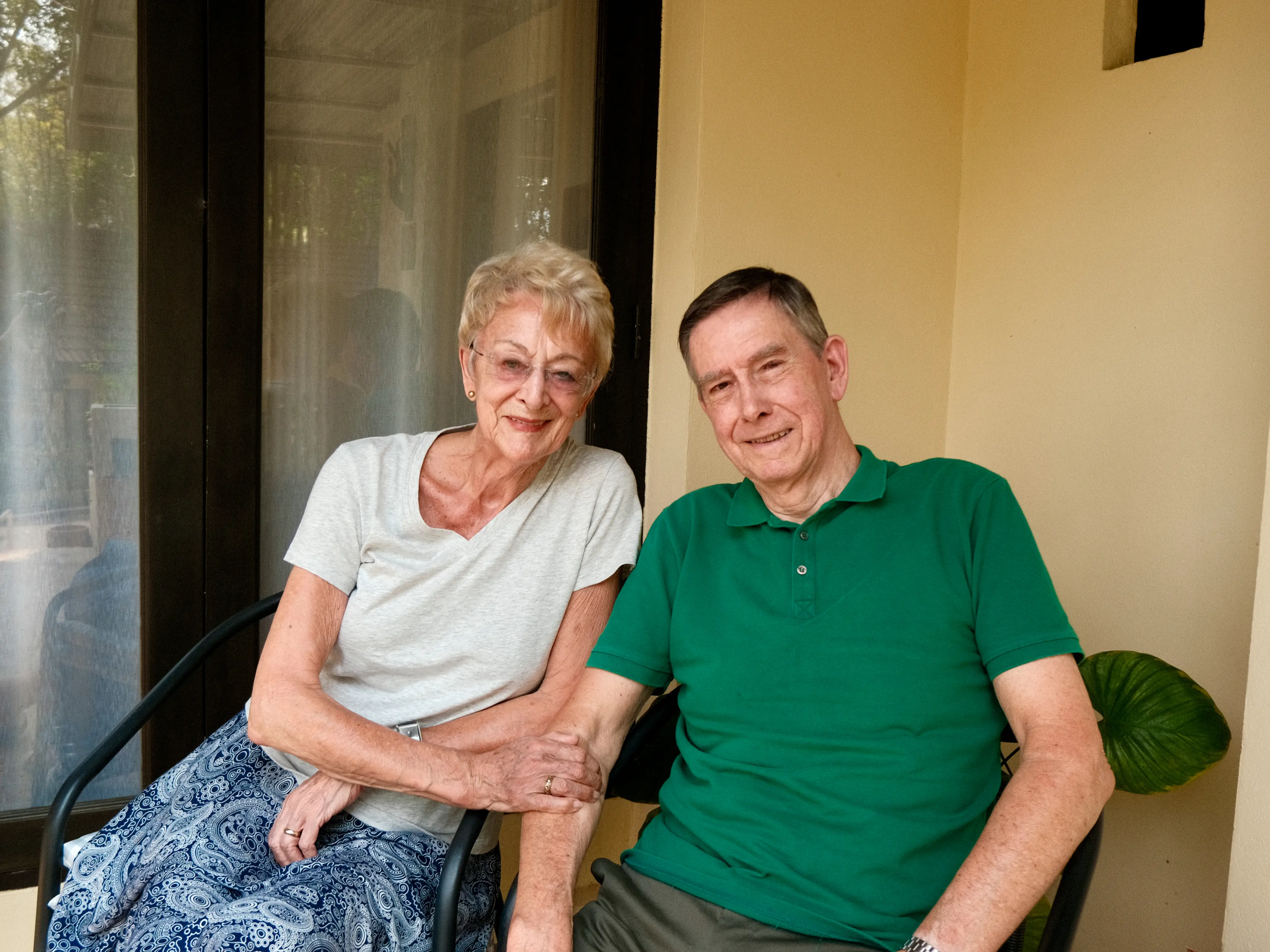 A couple posing for a photo outside their home in a retirement facility in Chiang Mai, Thailand.