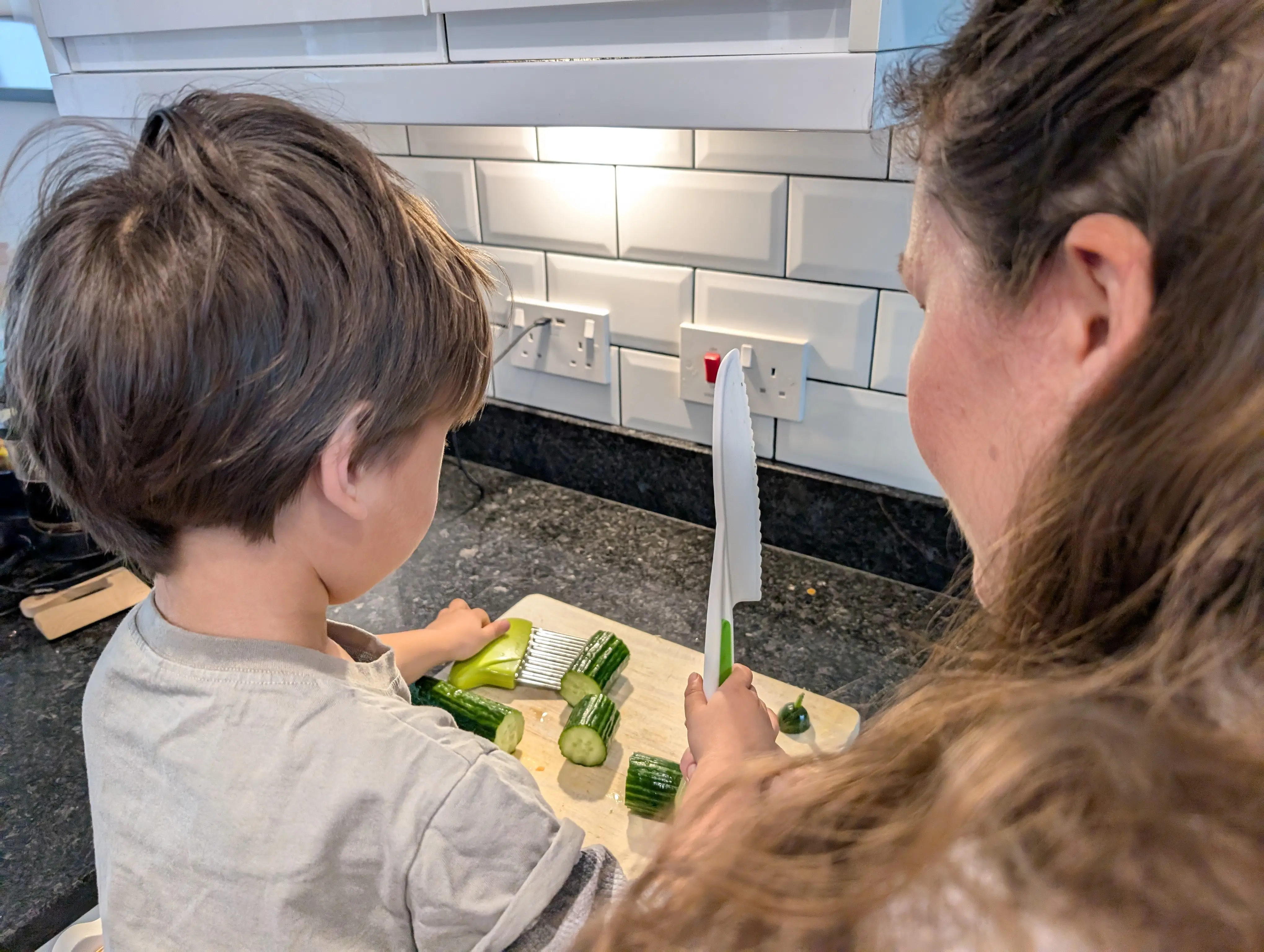 Toddler and mom cutting cucumber