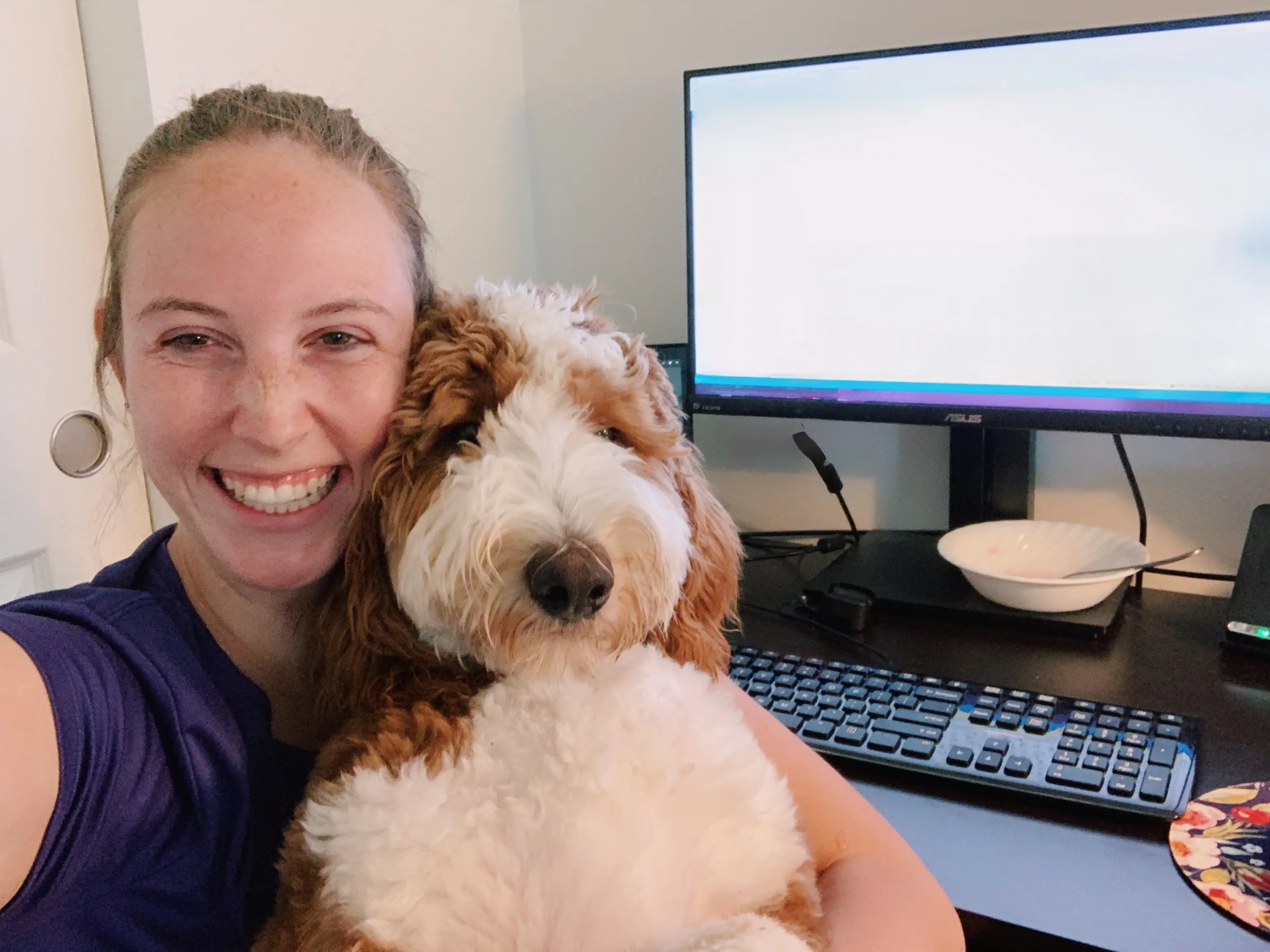 woman smiling with dog at computer