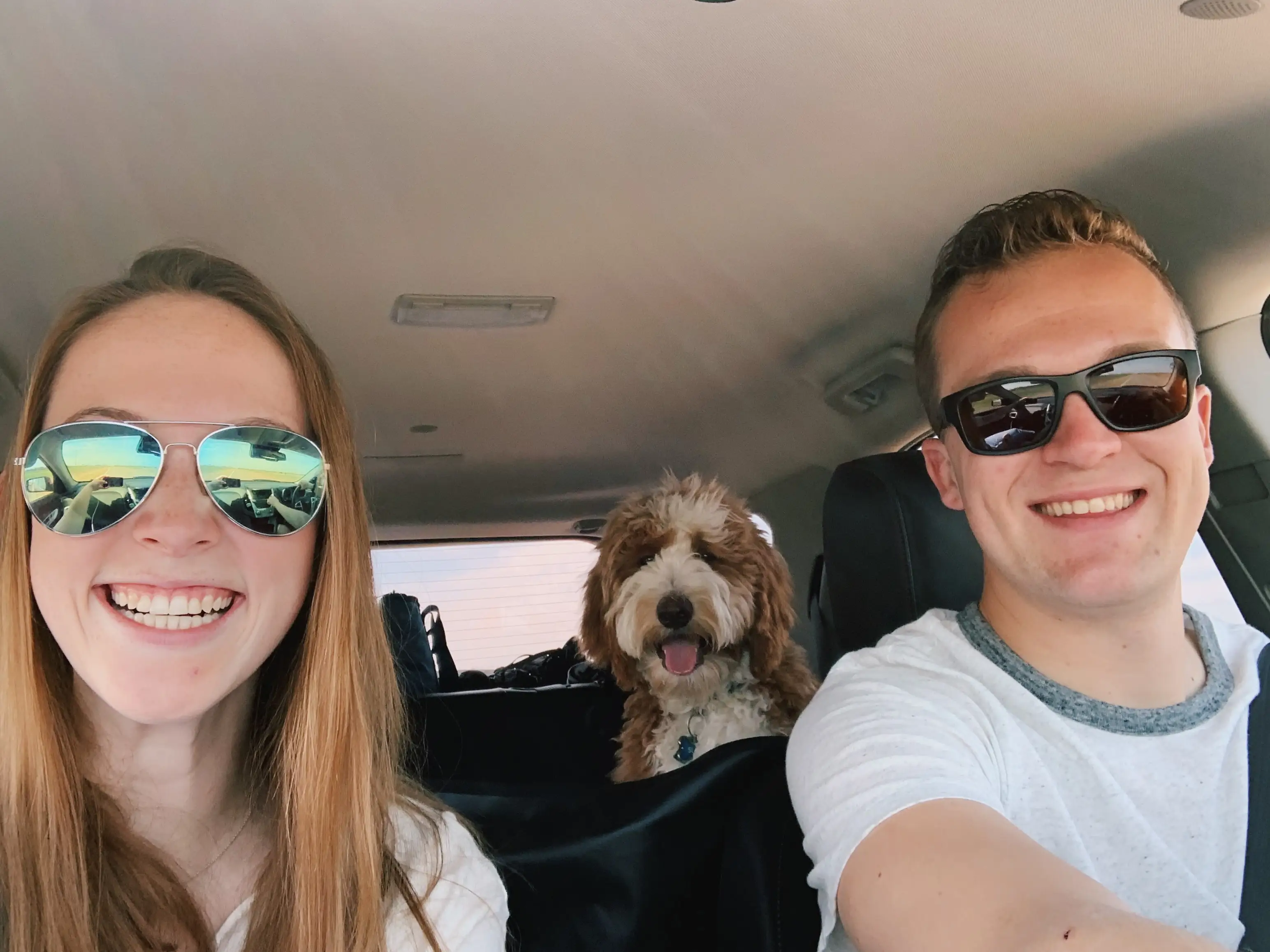 Woman smiling with man in car, dog in backseat