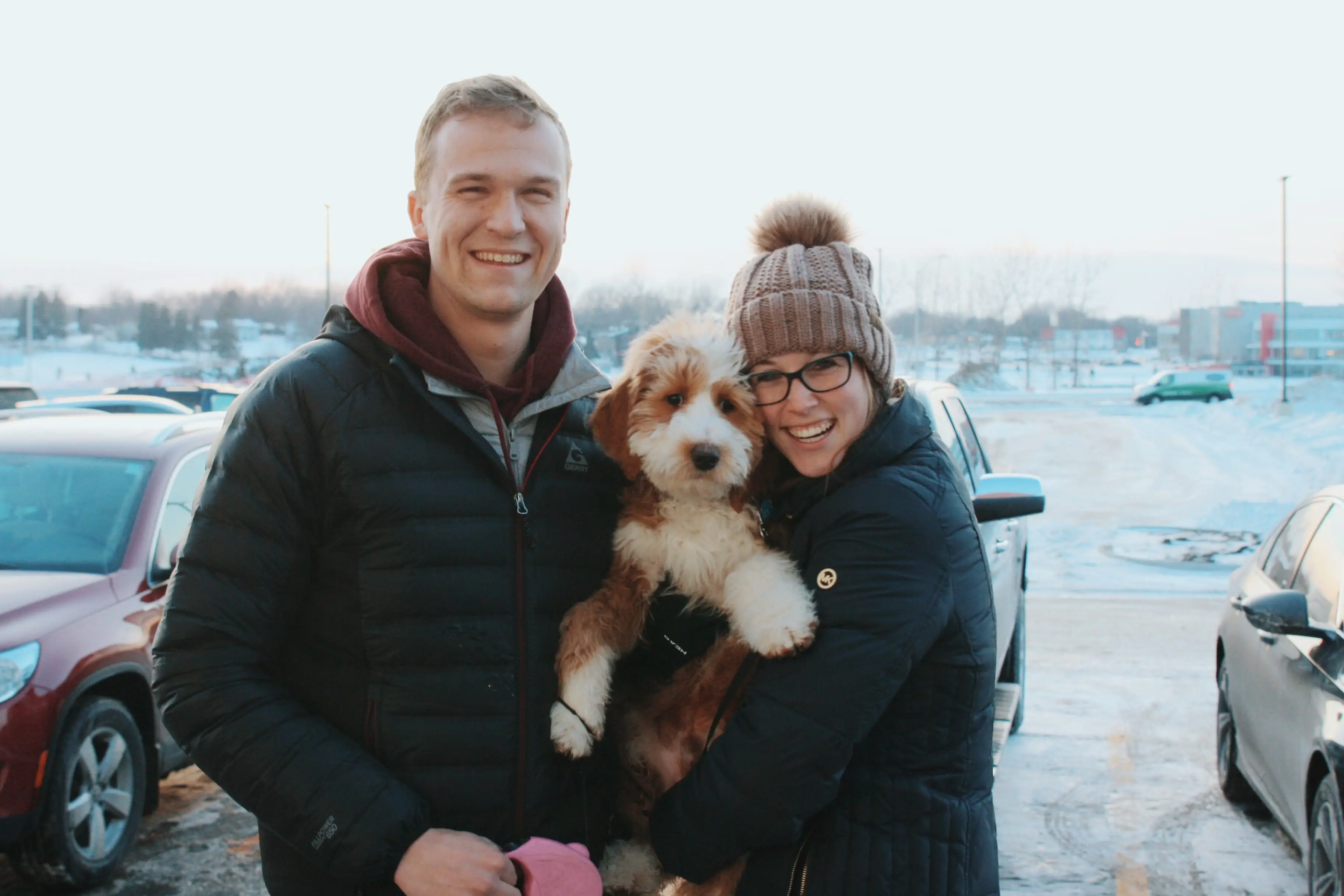 Woman an man smiling outside in winter time, holding dog