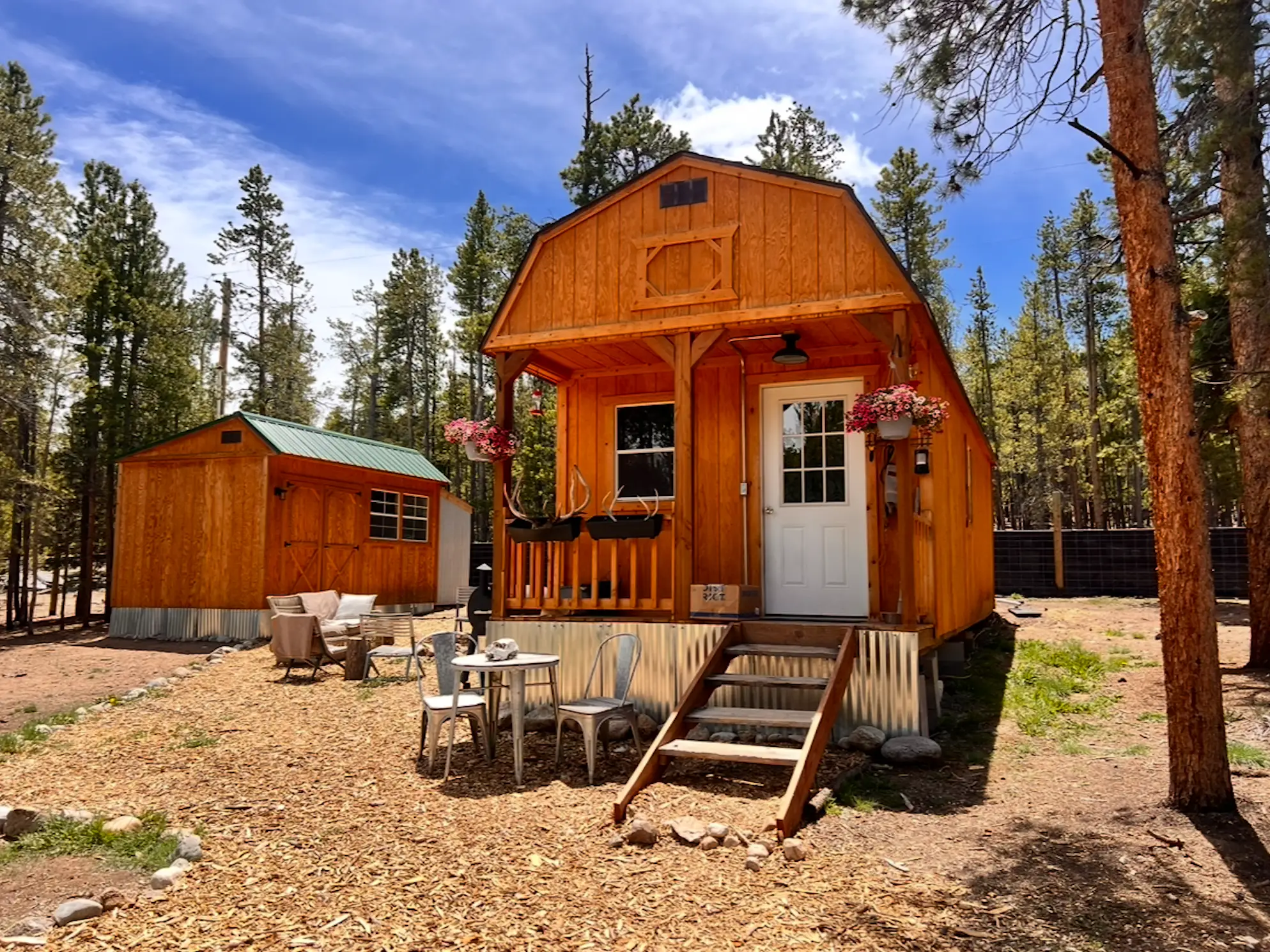 A wood tiny house with seating in front of it.