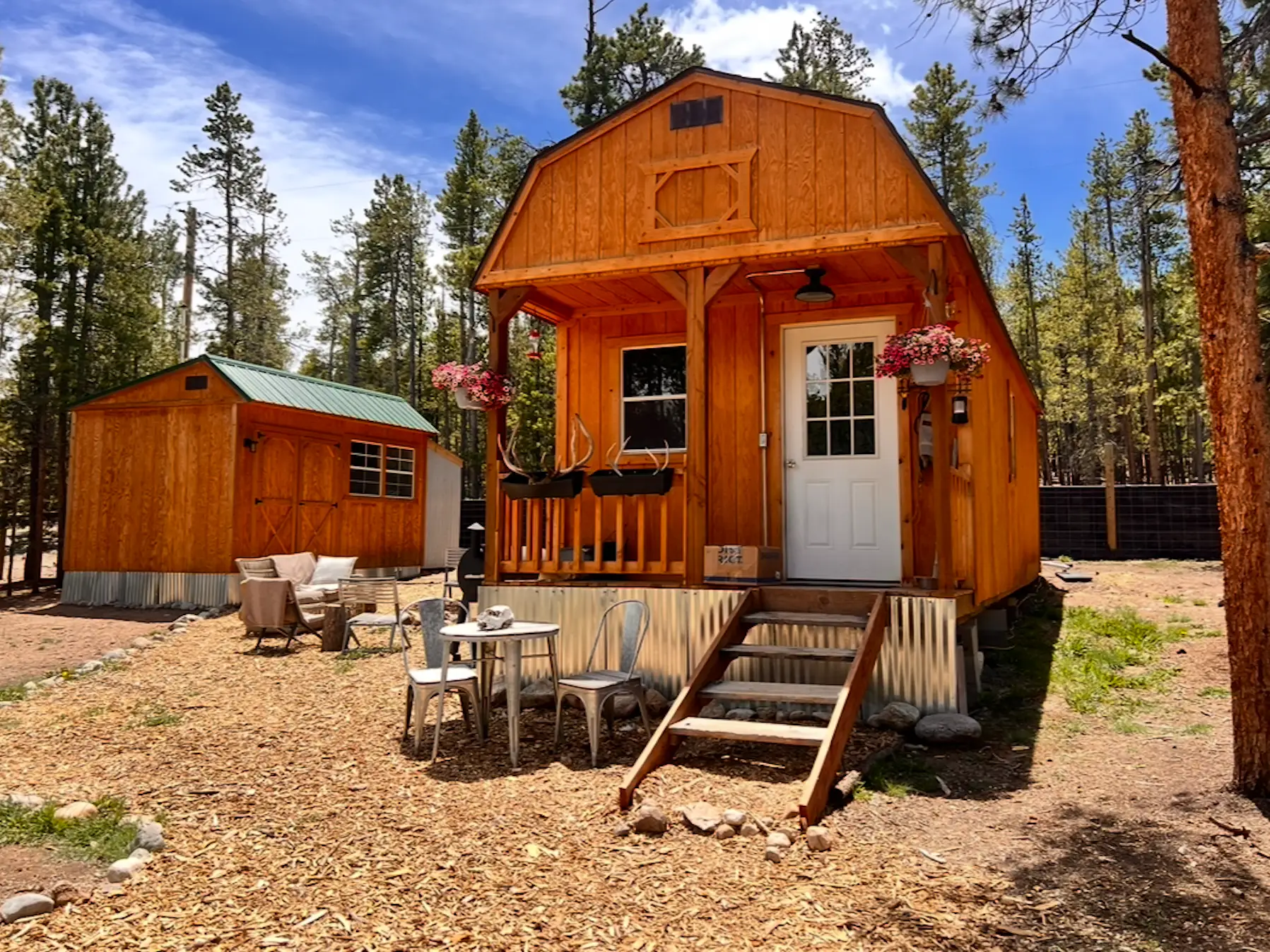 A wood tiny house with seating in front of it.