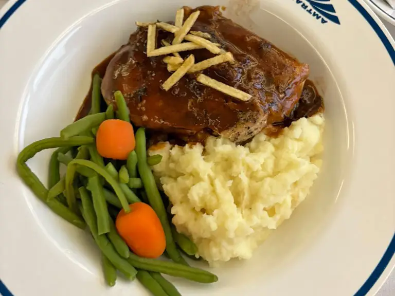 Chicken with gravy, mashed potatoes, carrots, and string beans on a plate.