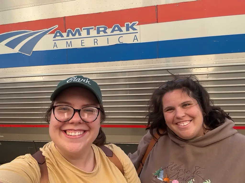 Paige and her sister stand in front of a train marked 