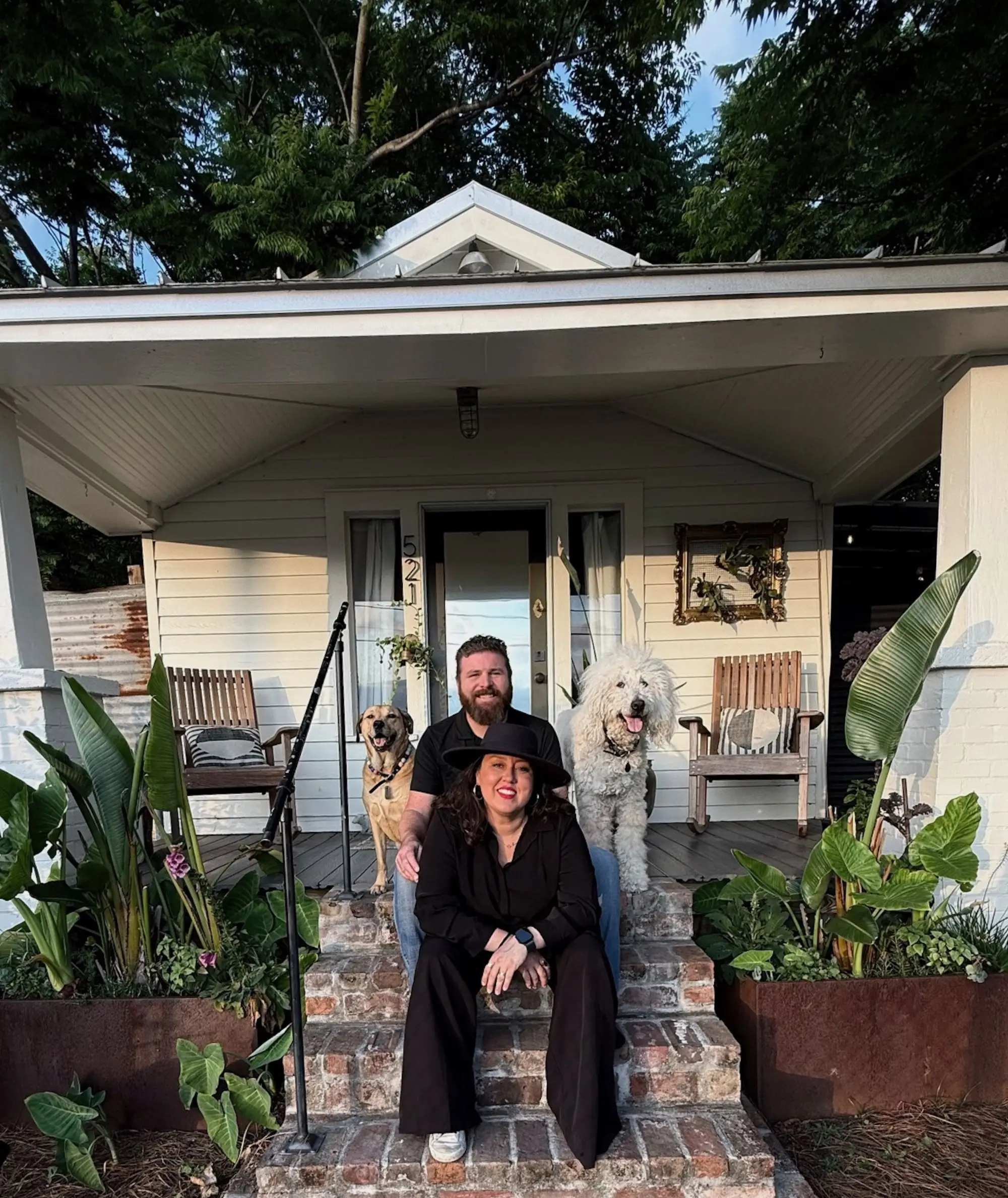 A couple sits on their porch with two dogs.