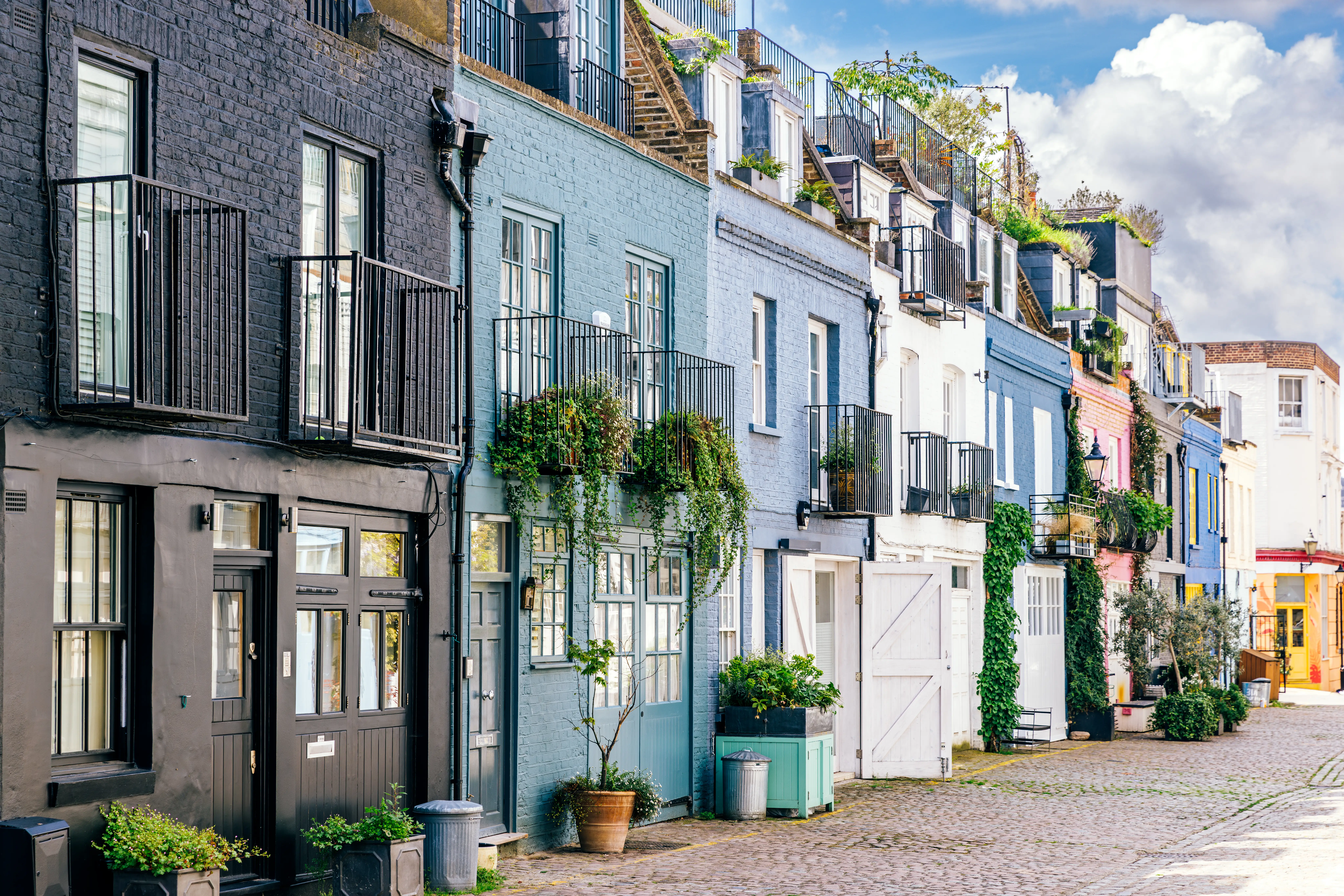 A mews street in London with colorful houses and plants.