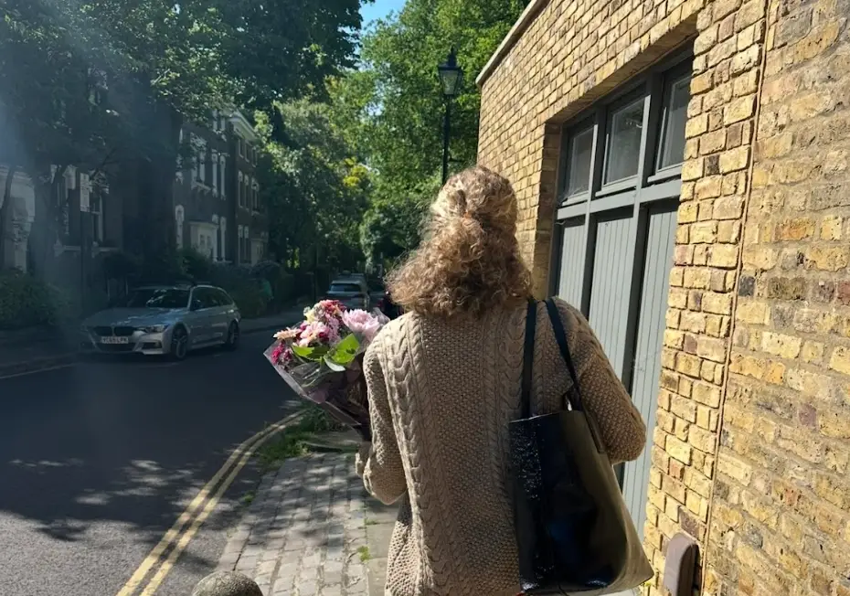 The writer walking down a street in London carrying a bouquet of flowers.