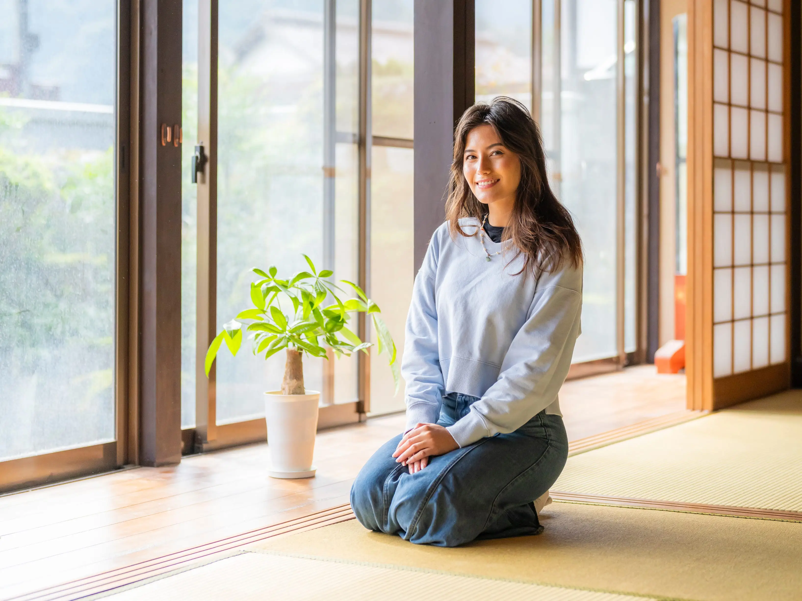 A woman kneeling on tatami mats in Japan.