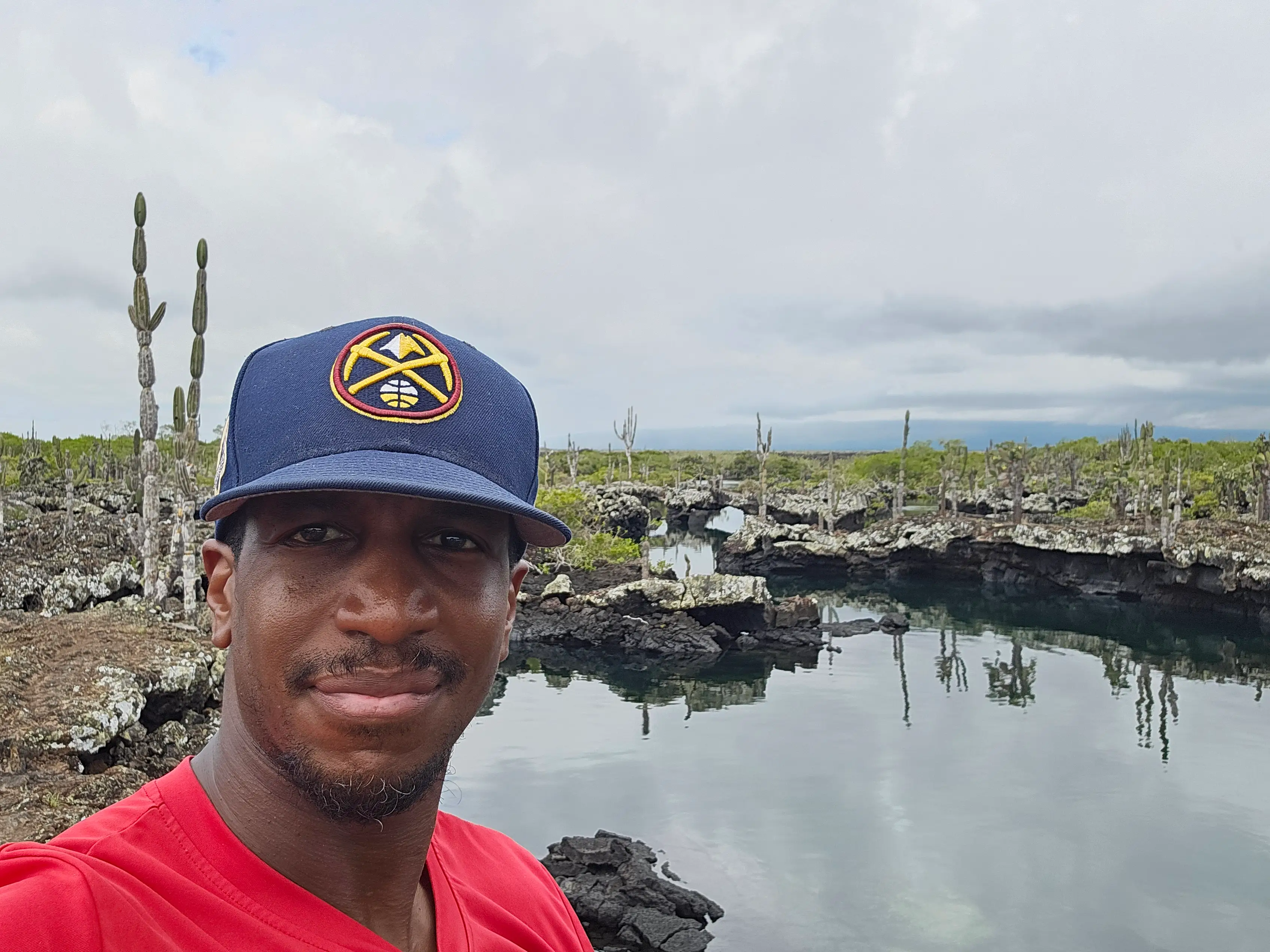 Man smiling with view of water, rocks behind him