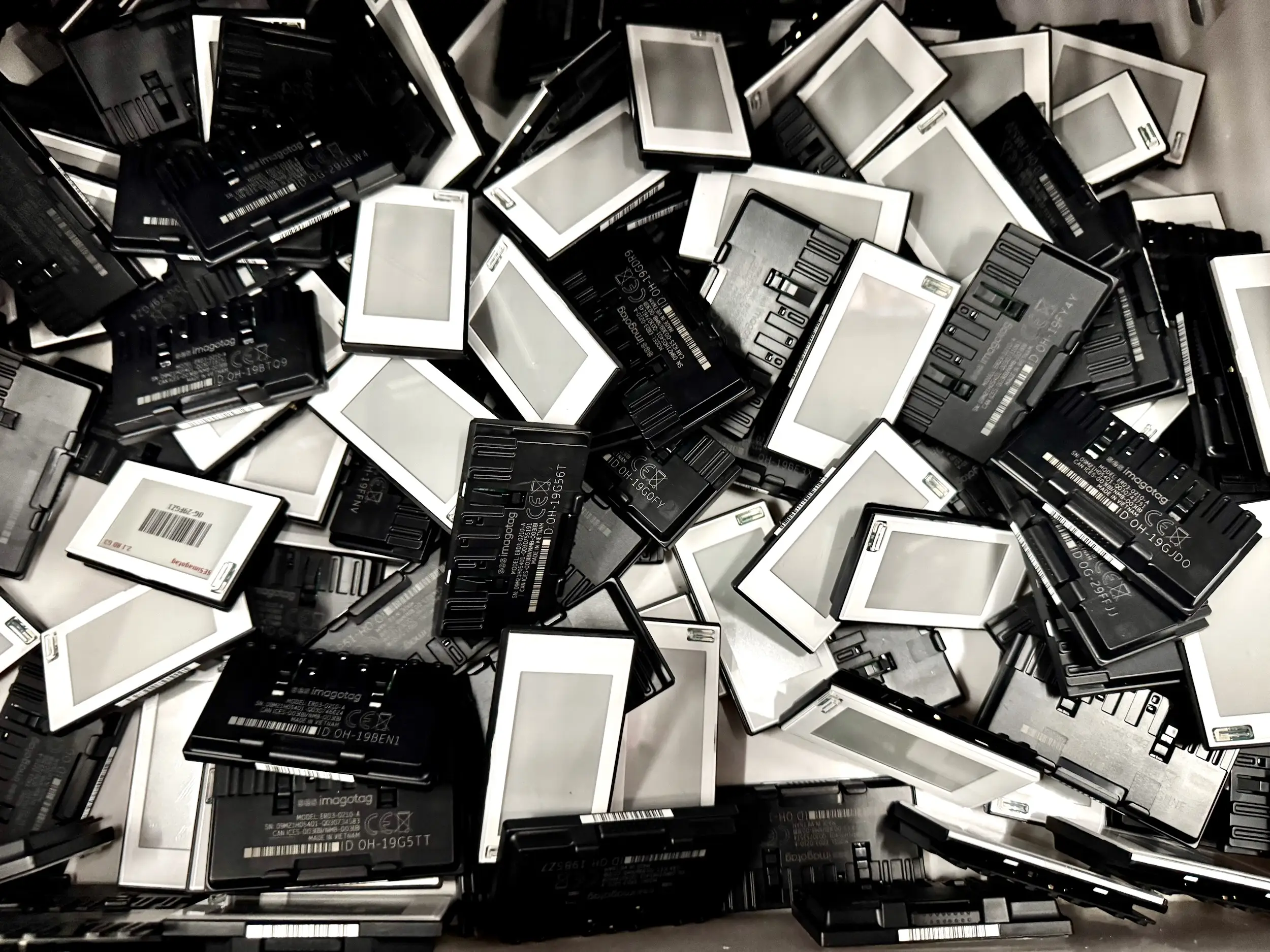 A close-up shows a pile of black and white electronic shelf labels stacked together.
