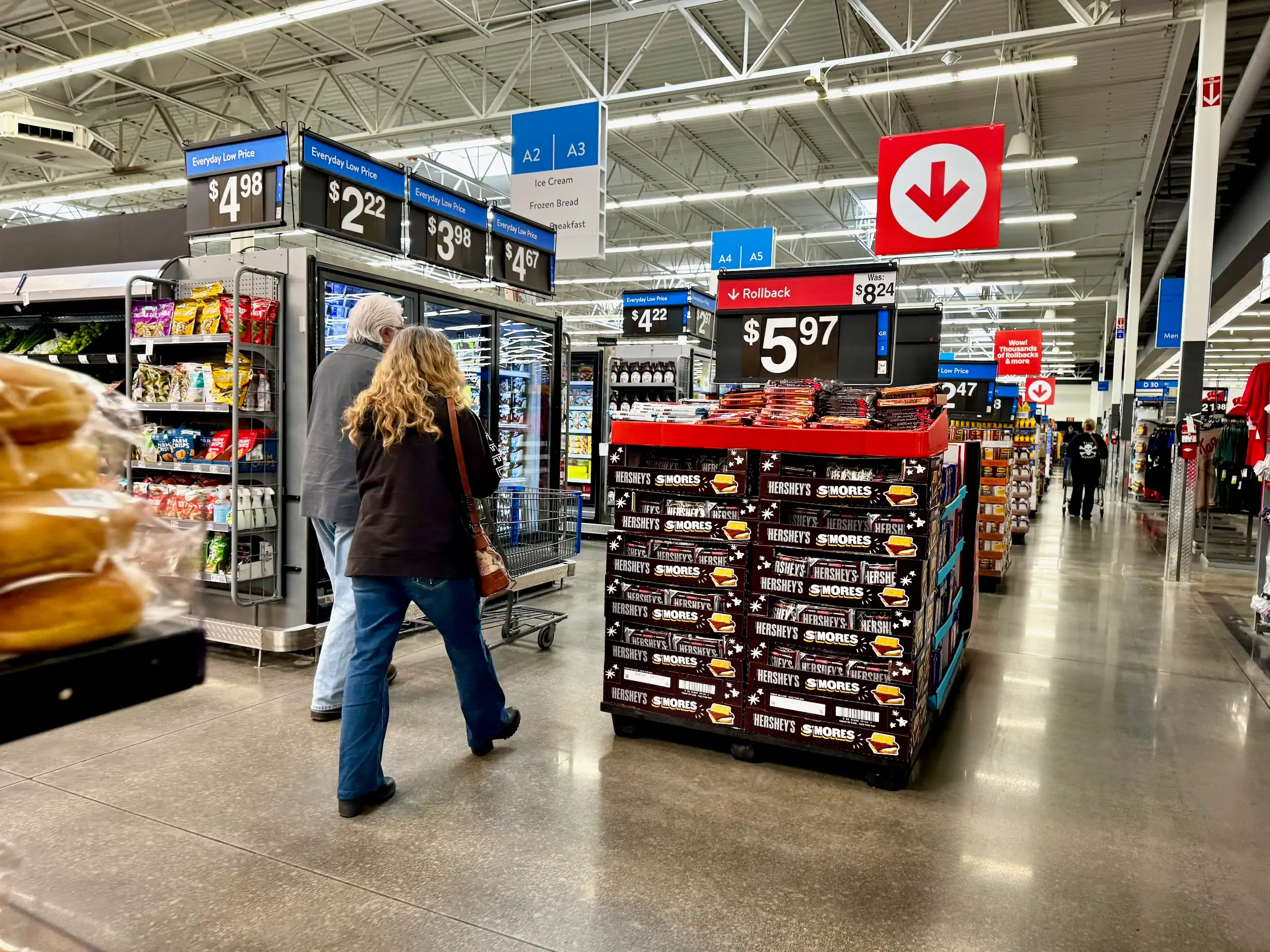 Shoppers walk past a display of Hershey's boxes under a rollback sign.
