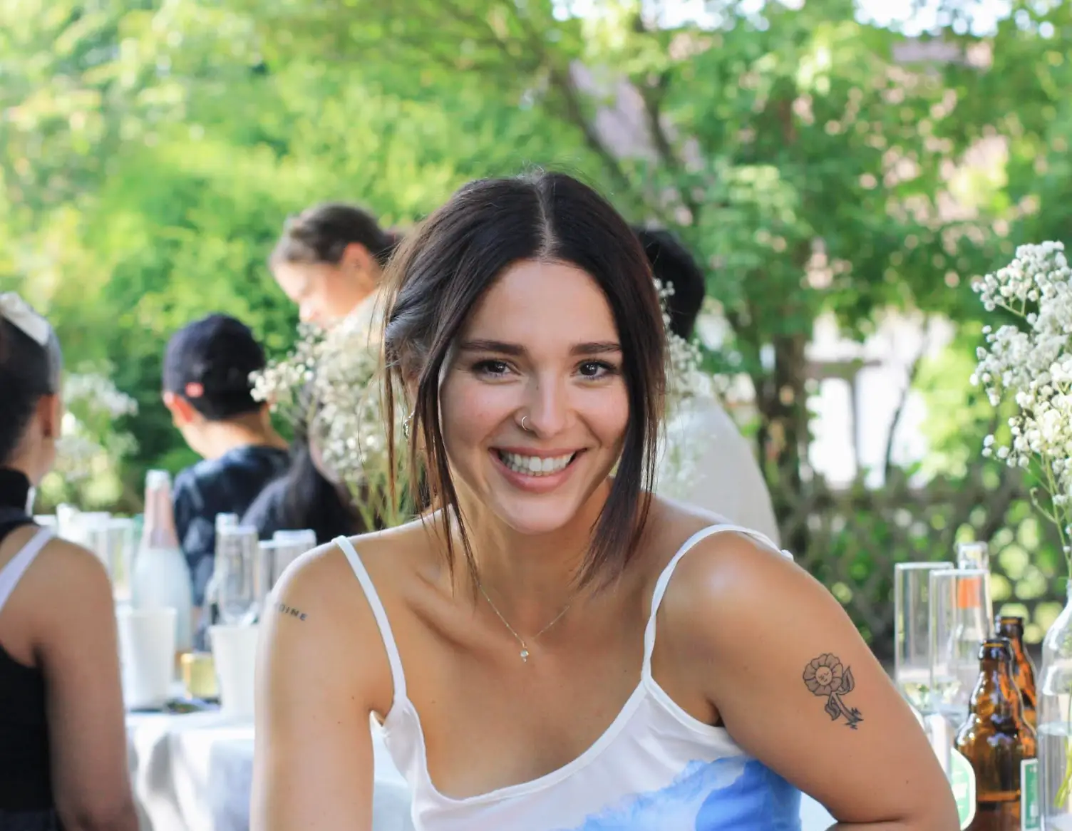 The writer wearing a white dress with blurry trees in the background.