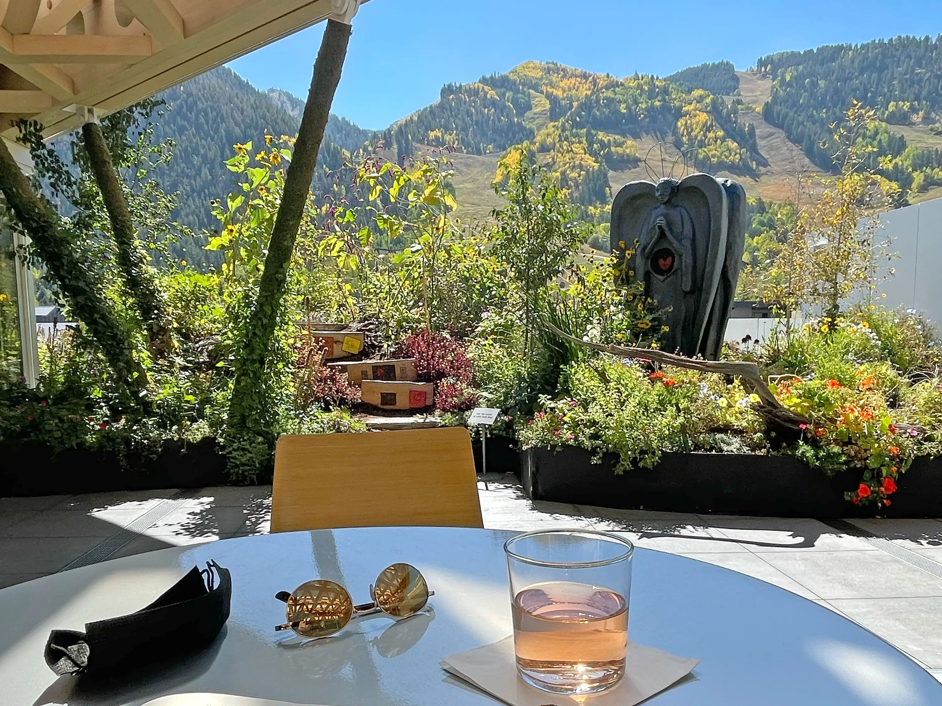 Sunglasses and a drink on a table at an outdoor café that looks out at mountains.
