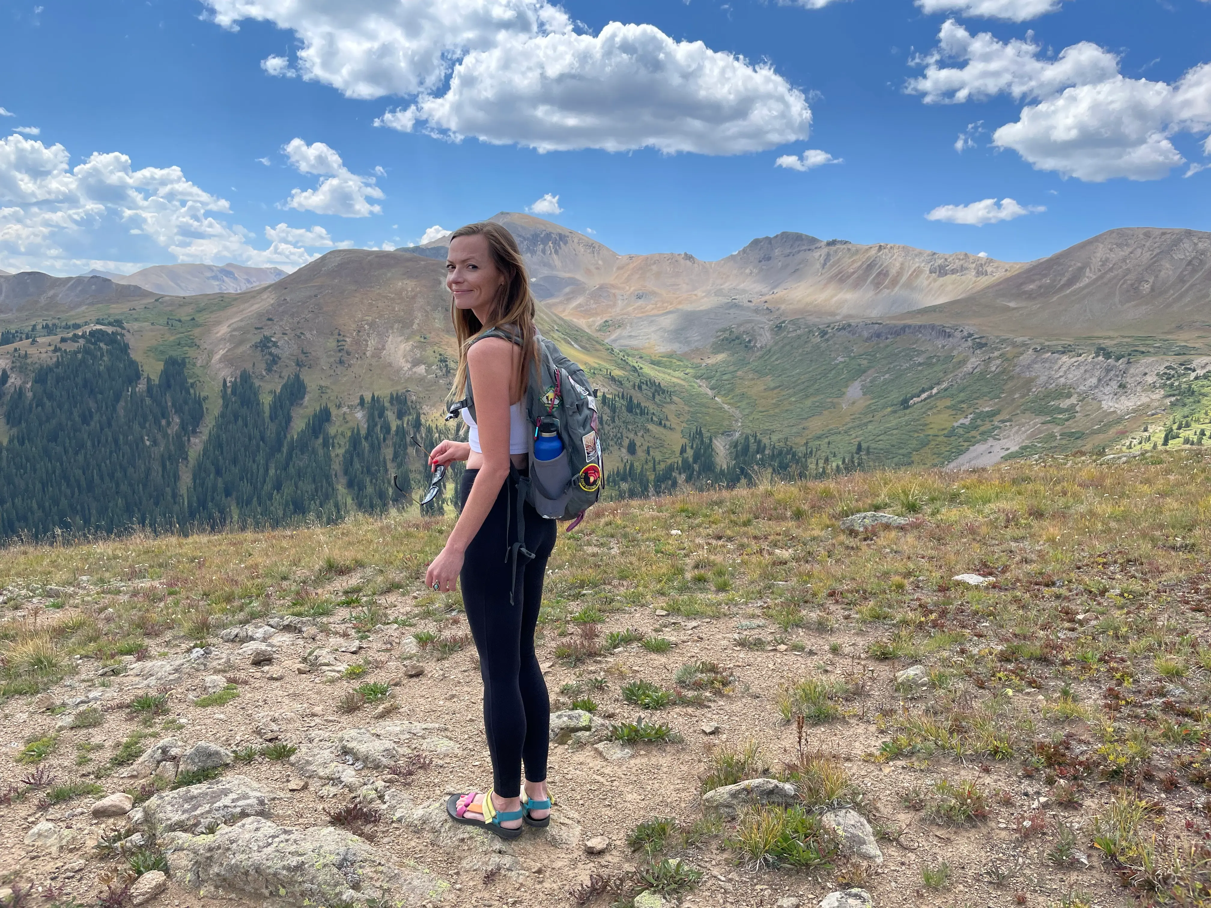 Emily stands at an overlook with gorgeous mountains behind her.