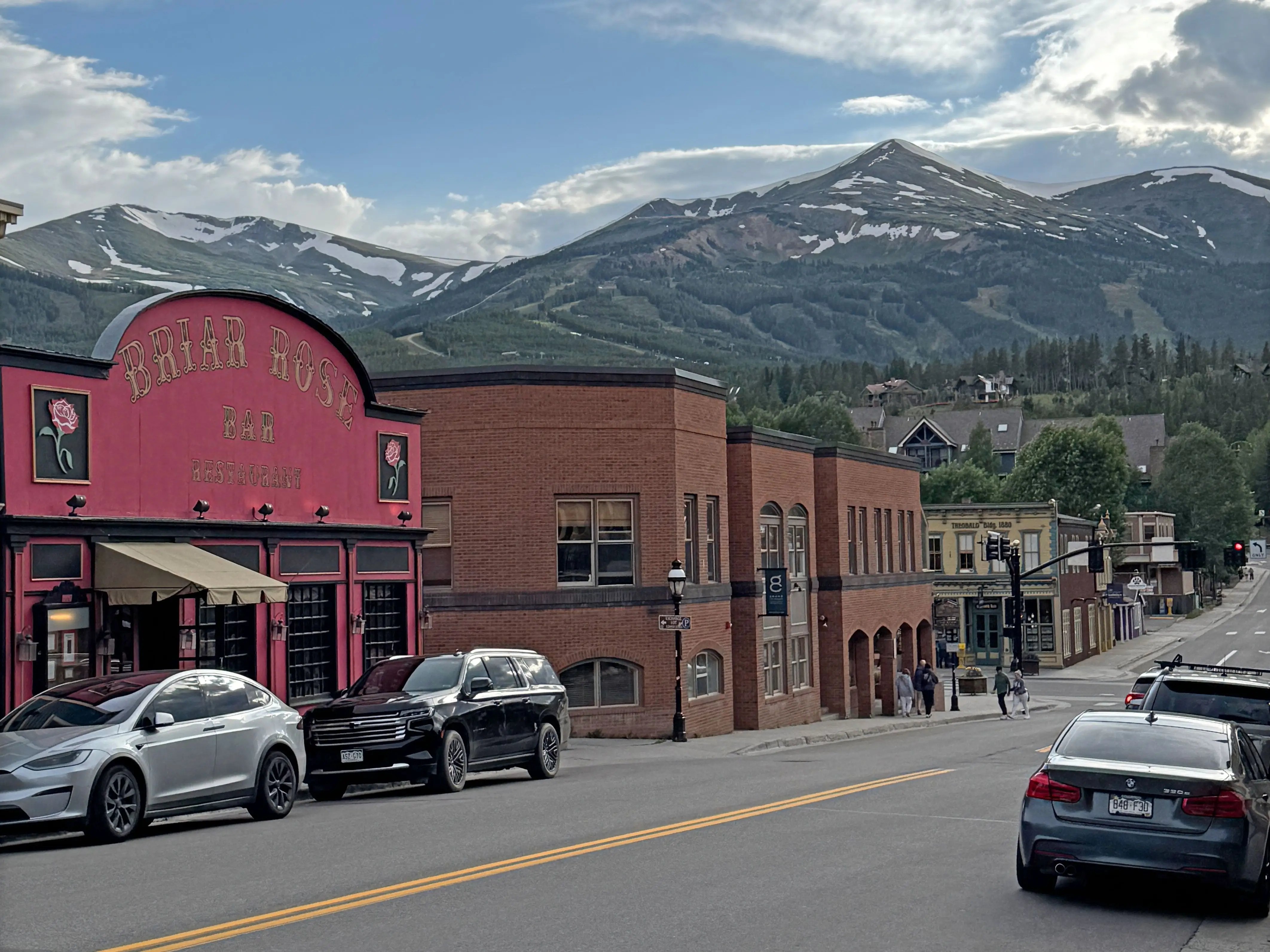 A main street in Breckenridge, Colorado, lined with buildings. There are mountains in the distance.
