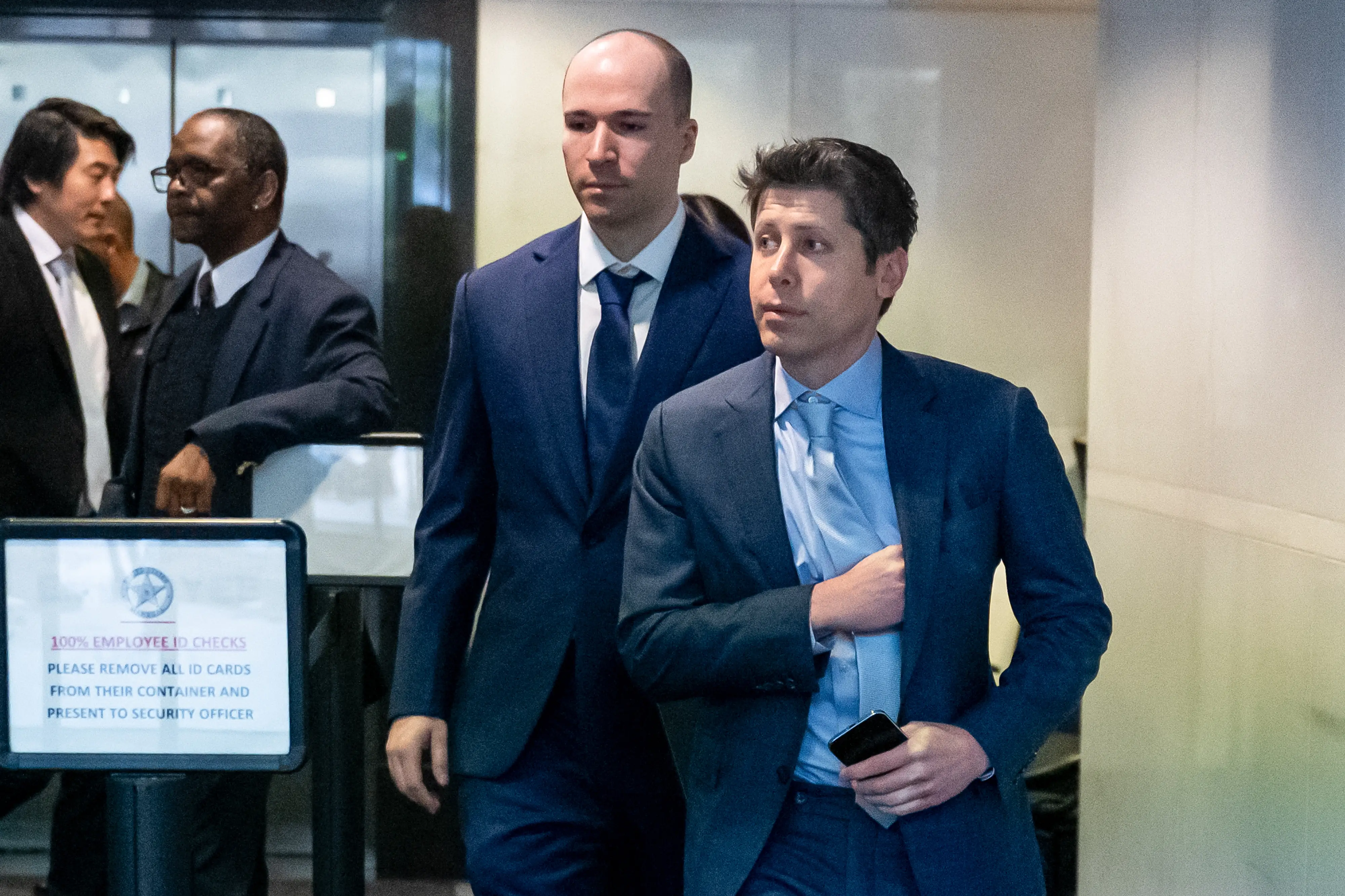 Sam Altman walking with Greg Brockman behind him