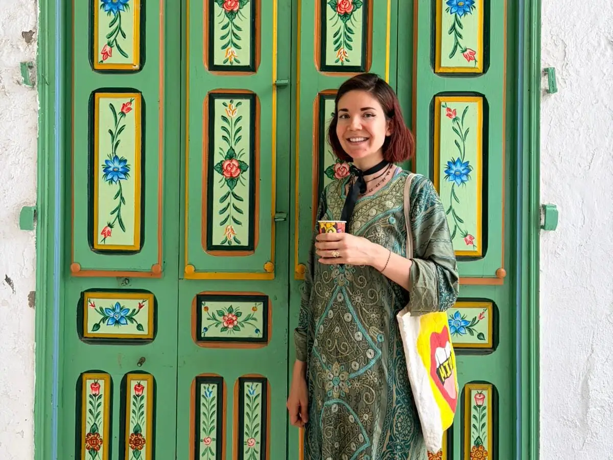 The author poses in front of a colorful piece of furniture.