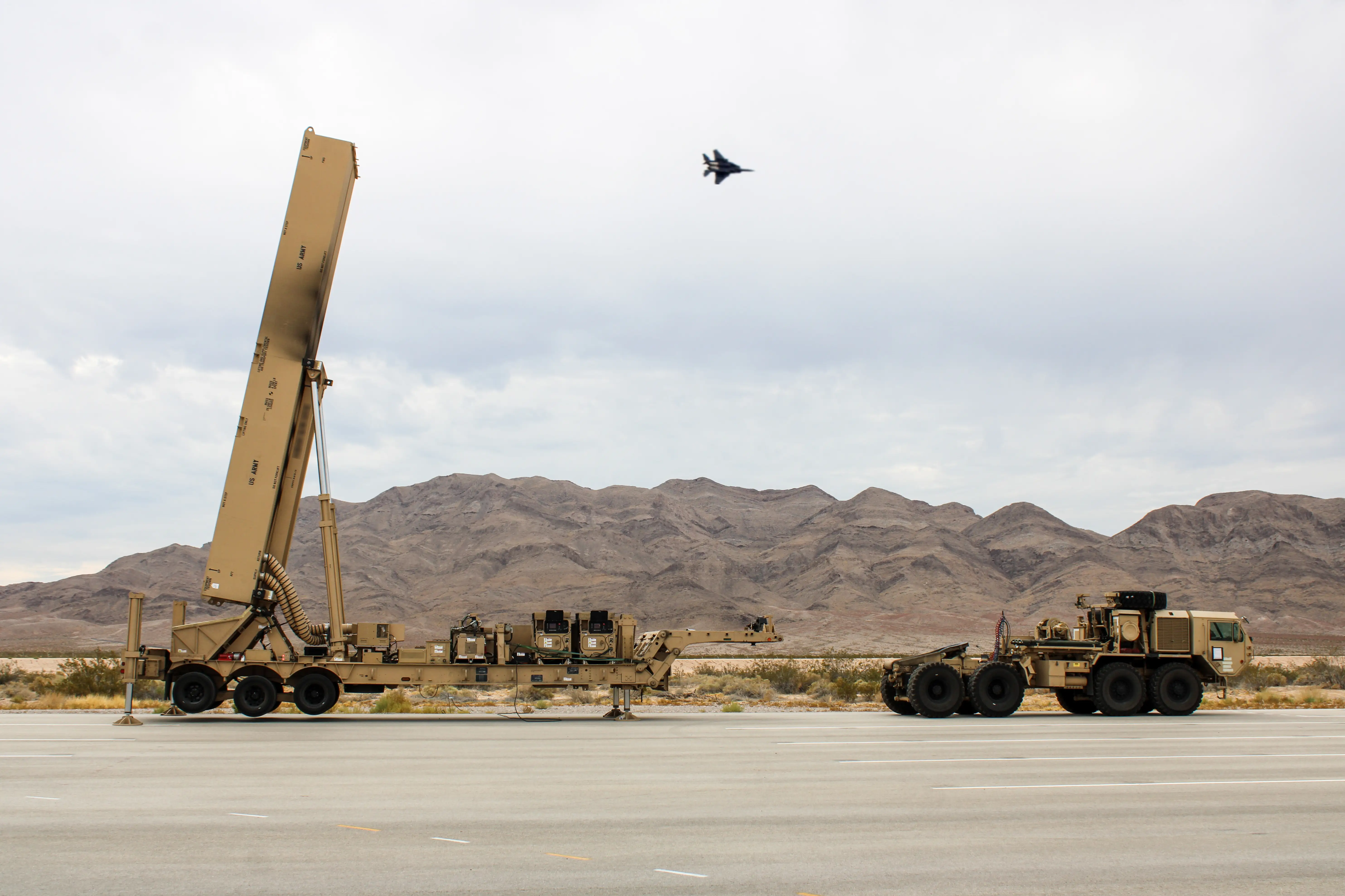 An Air Force F-16 flies over a Dark Eagle Long Range Hypersonic Weapon vehicle launcher during a training exercise at Nevada's Nellis Air Force Base., Aug. 2, 2024.