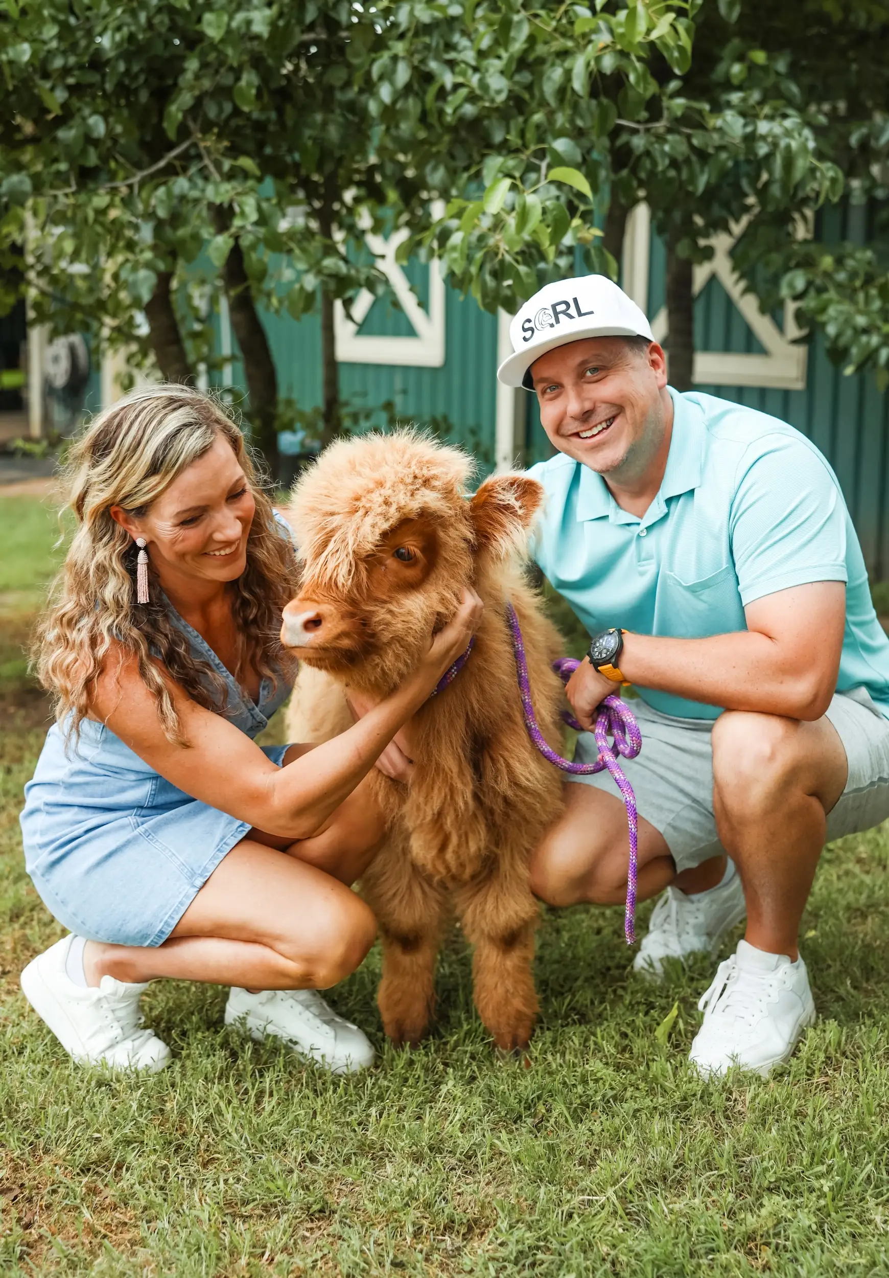 A man and woman kneeling with a cow.