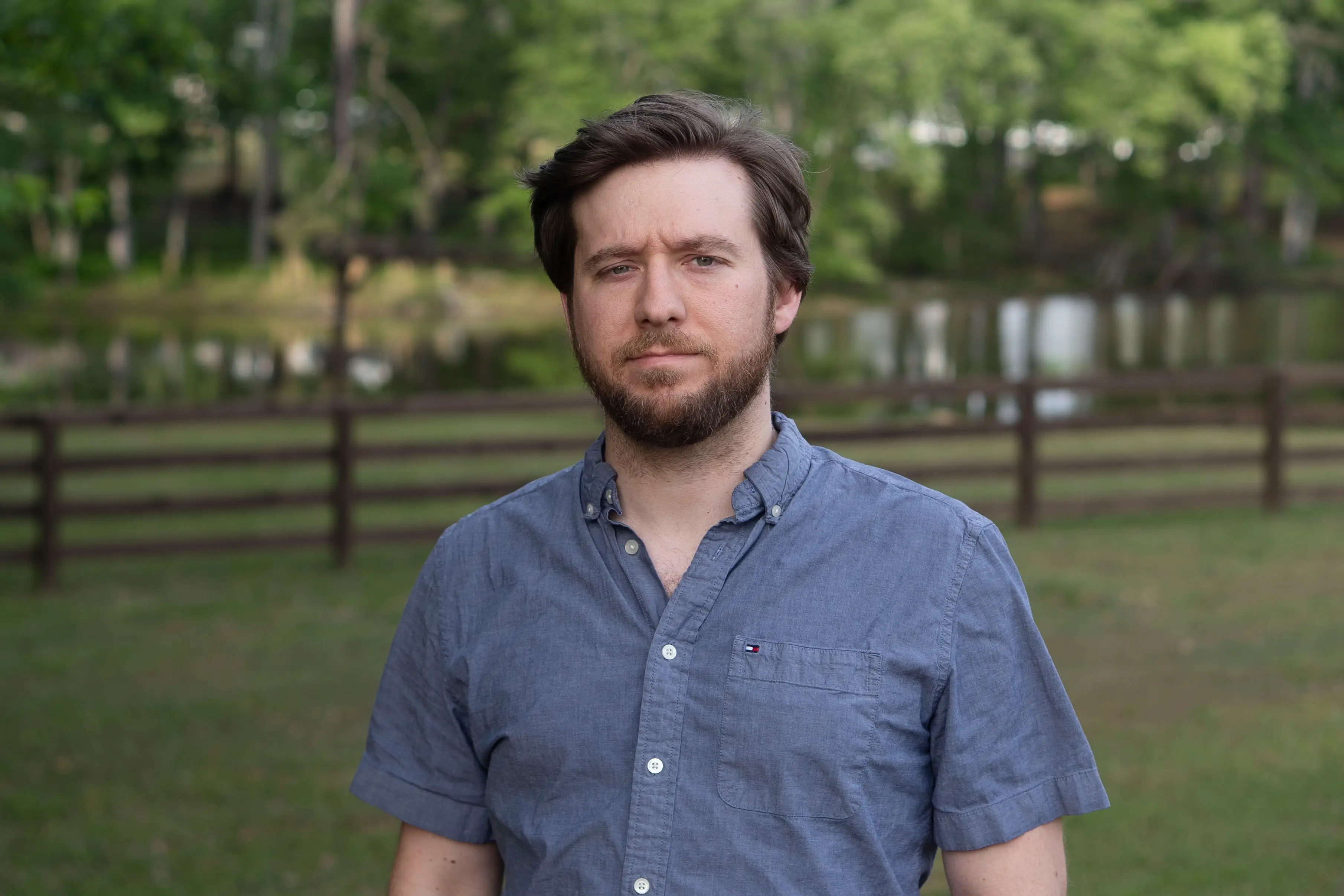 Jesse Brooks stands in front of fence and wooded area.