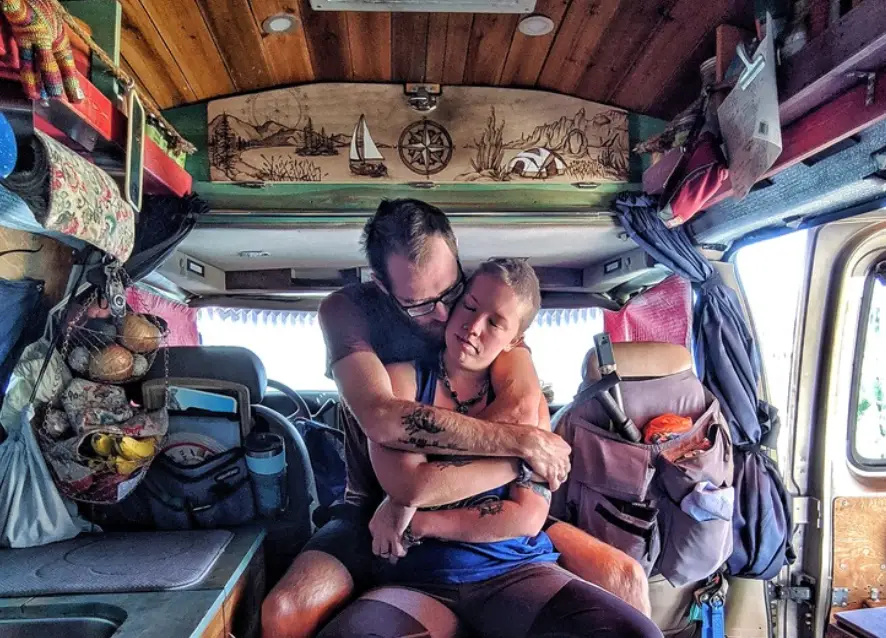 The writer's partner holding her in the middle of a camper van, with the door open and sunlight streaming in.