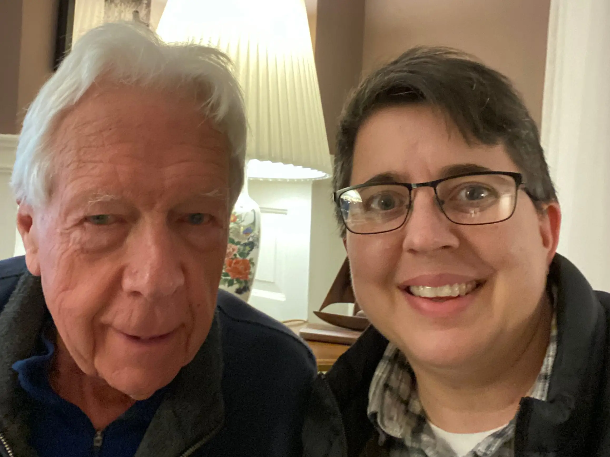 An older man and a younger woman are taking a selfie