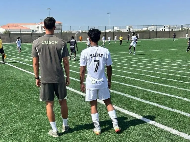 A soccer coach and player on a field in Dubai.