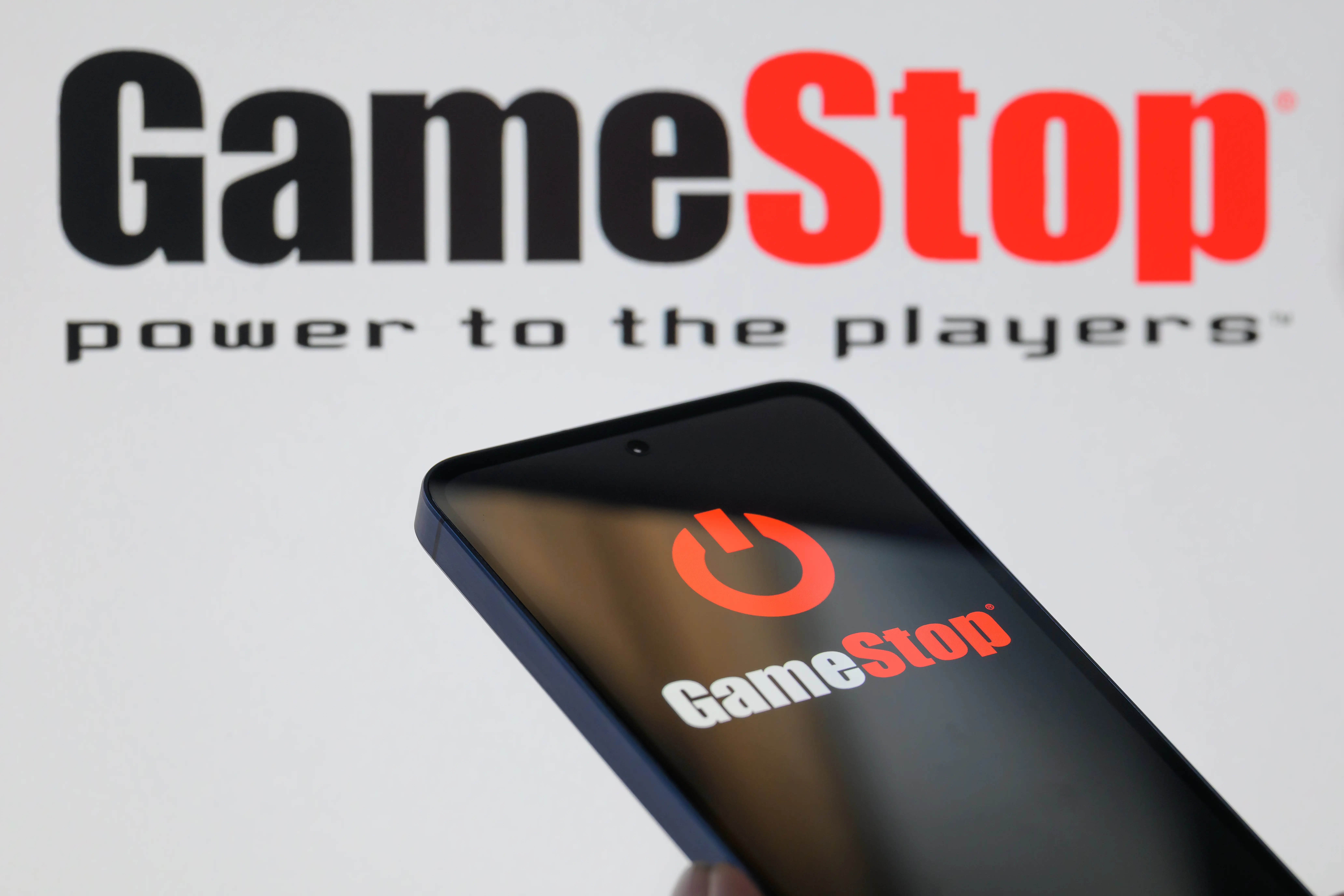 A phone and wall featuring the GameStop logo.