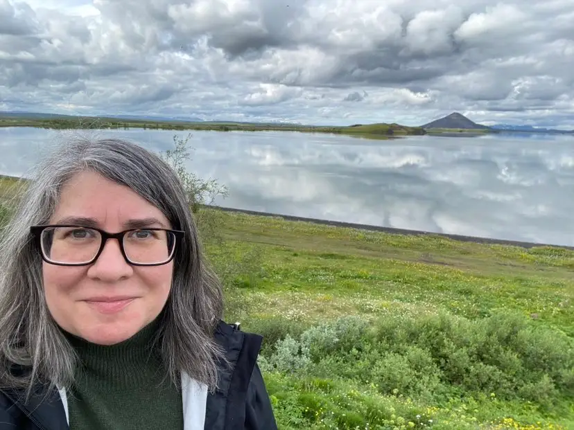 A woman taking a selfie in front of greenery in Iceland.