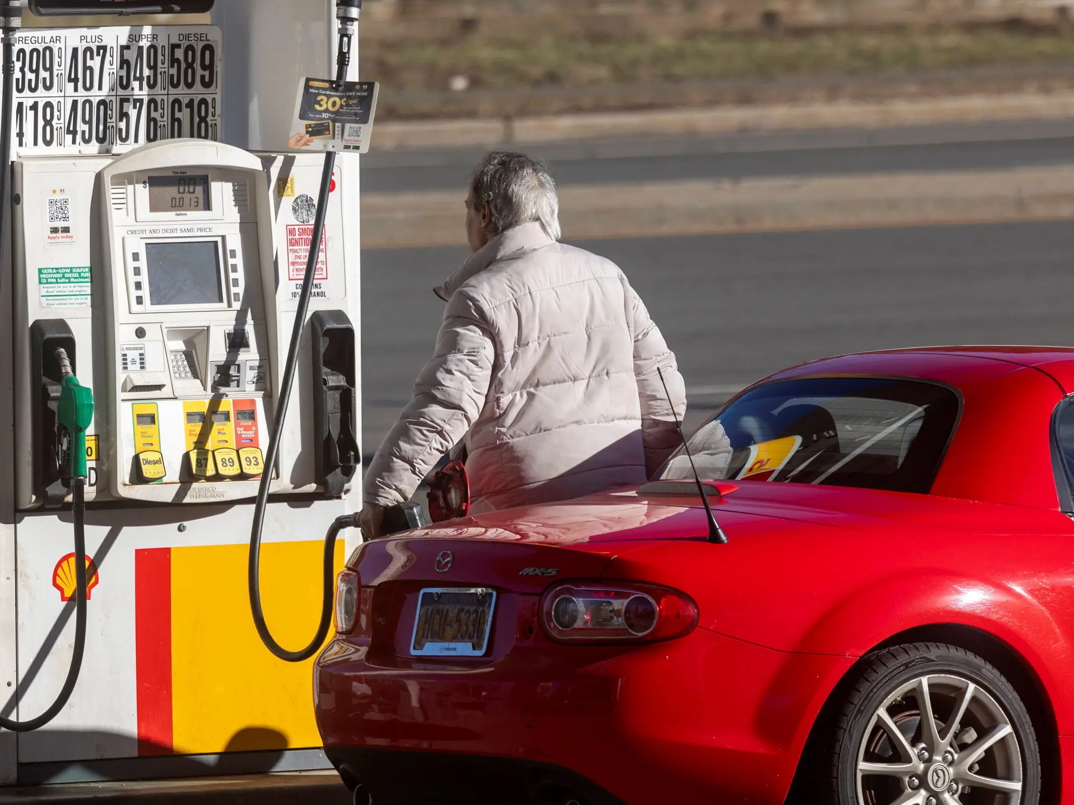 Person pumping gas into their vehicle at a gas station