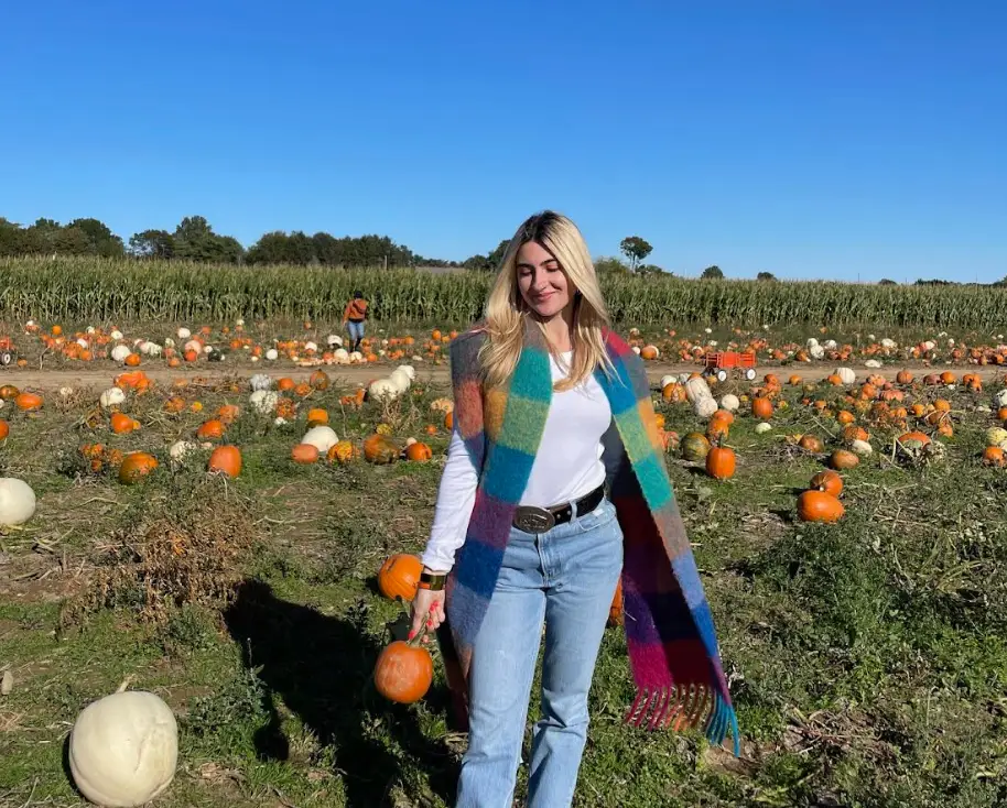 The writer standing in a pumpkin patch with a blue sky in the background.