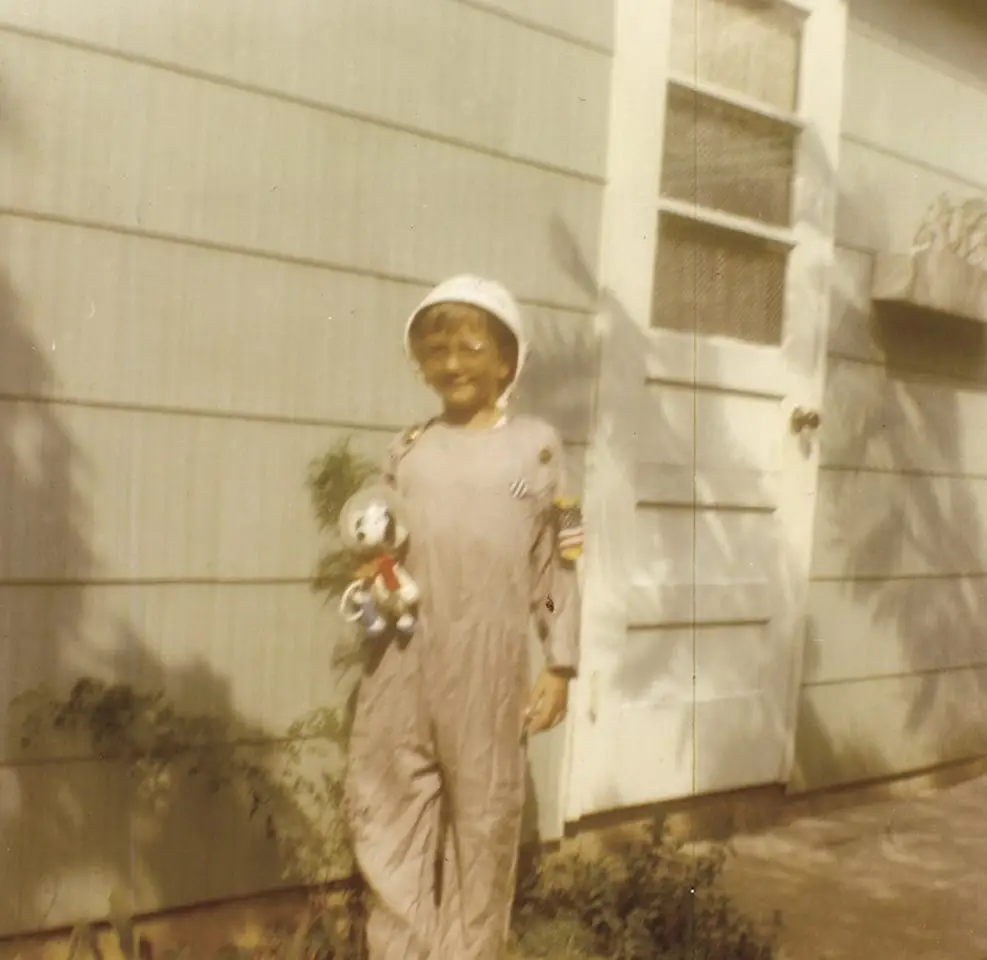 An old photo showing Mike Massimino as a kid holding a Snoopy astronaut.